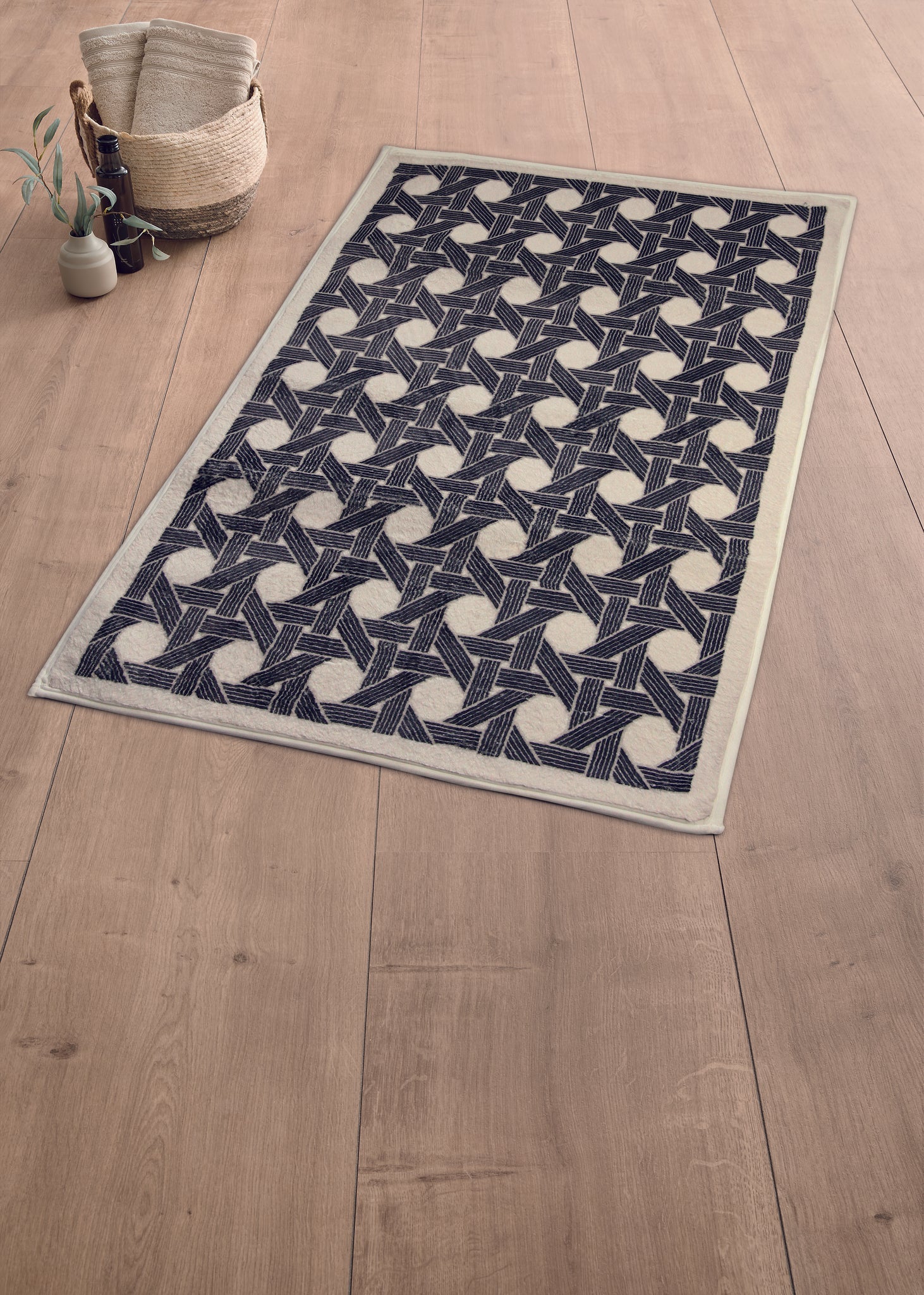 Schwarze Badematte mit geometrischem Muster auf großem hellem Holzboden