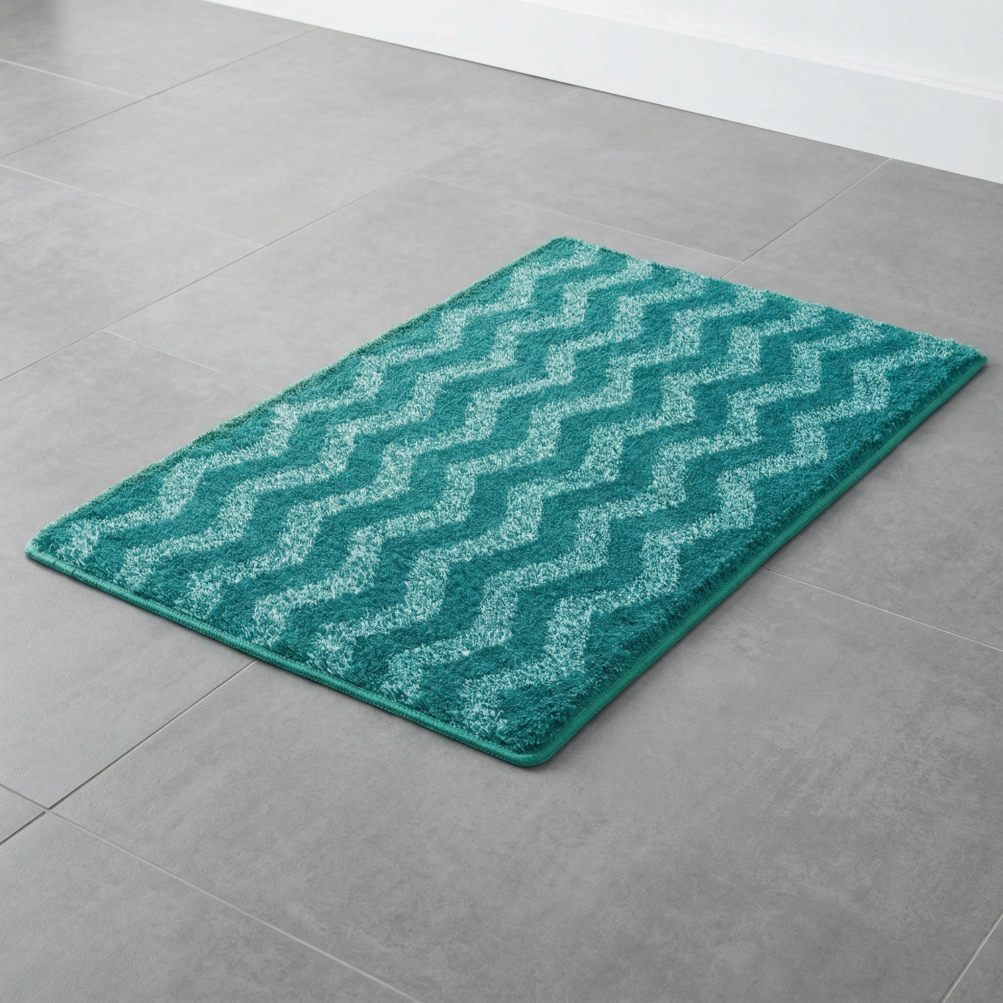 Türkisfarbener Badteppich mit Zickzackmuster auf grauen Fliesenboden