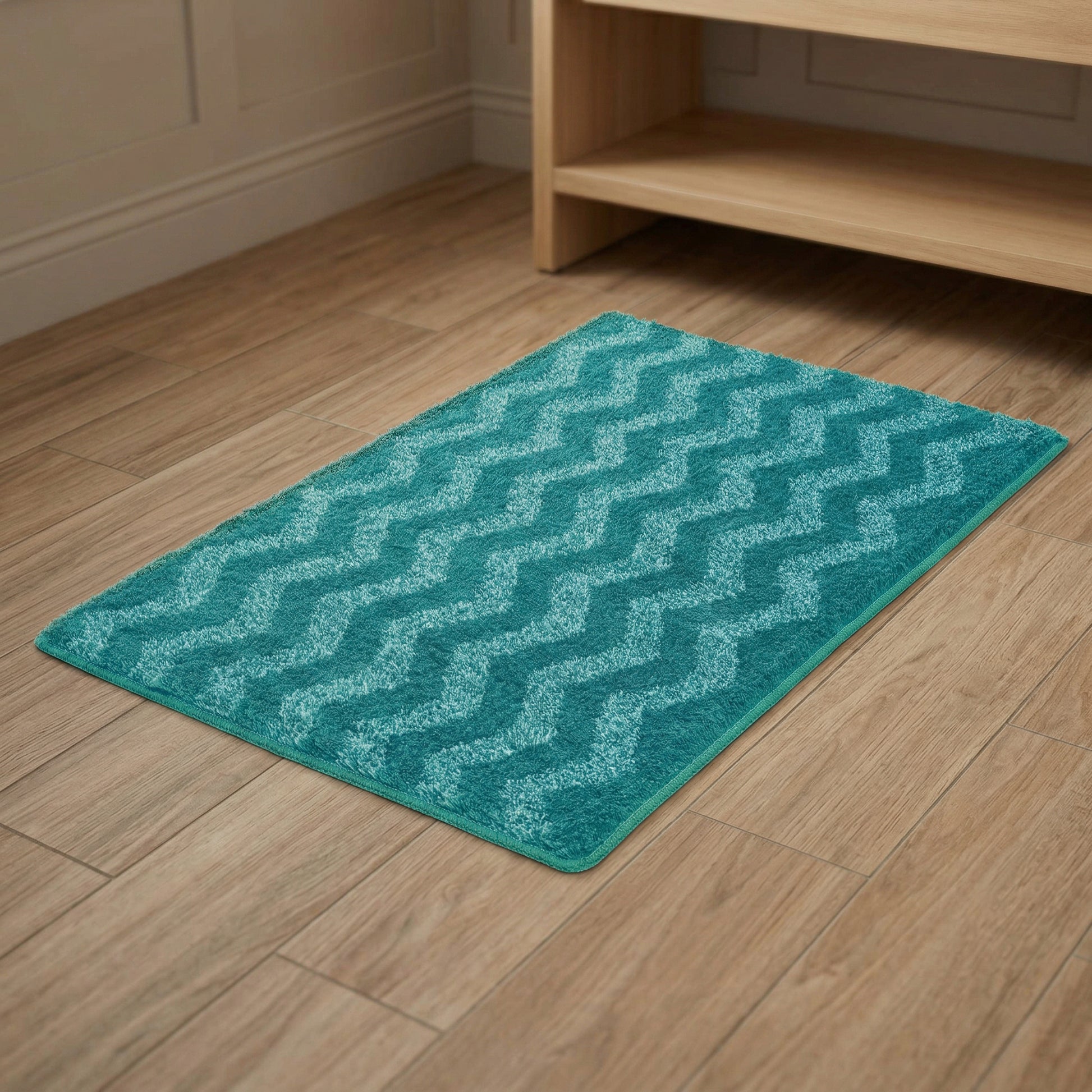 Türkisfarbene Badematte mit Zickzackmuster liegend auf hellem Holzboden