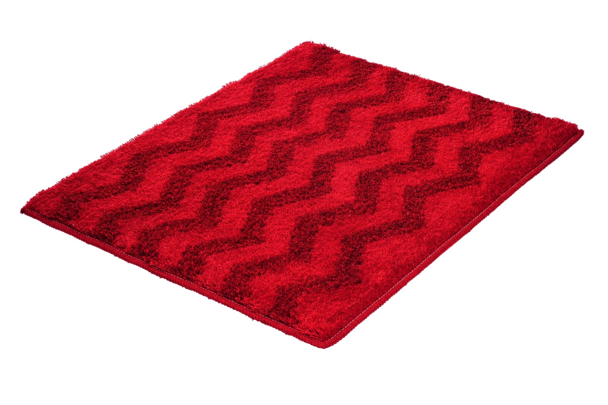 Badteppich ZACK Rubin 55 x 65 cm in Rot mit Zickzack-Struktur liegt auf weißem Hintergrund.