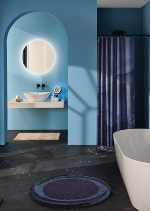 Badezimmer in blauen Farben und rundem Badteppich.