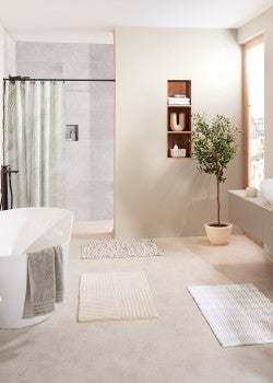 Badezimmer in hellen Farben und zwei Badteppichen in Sandtönen.