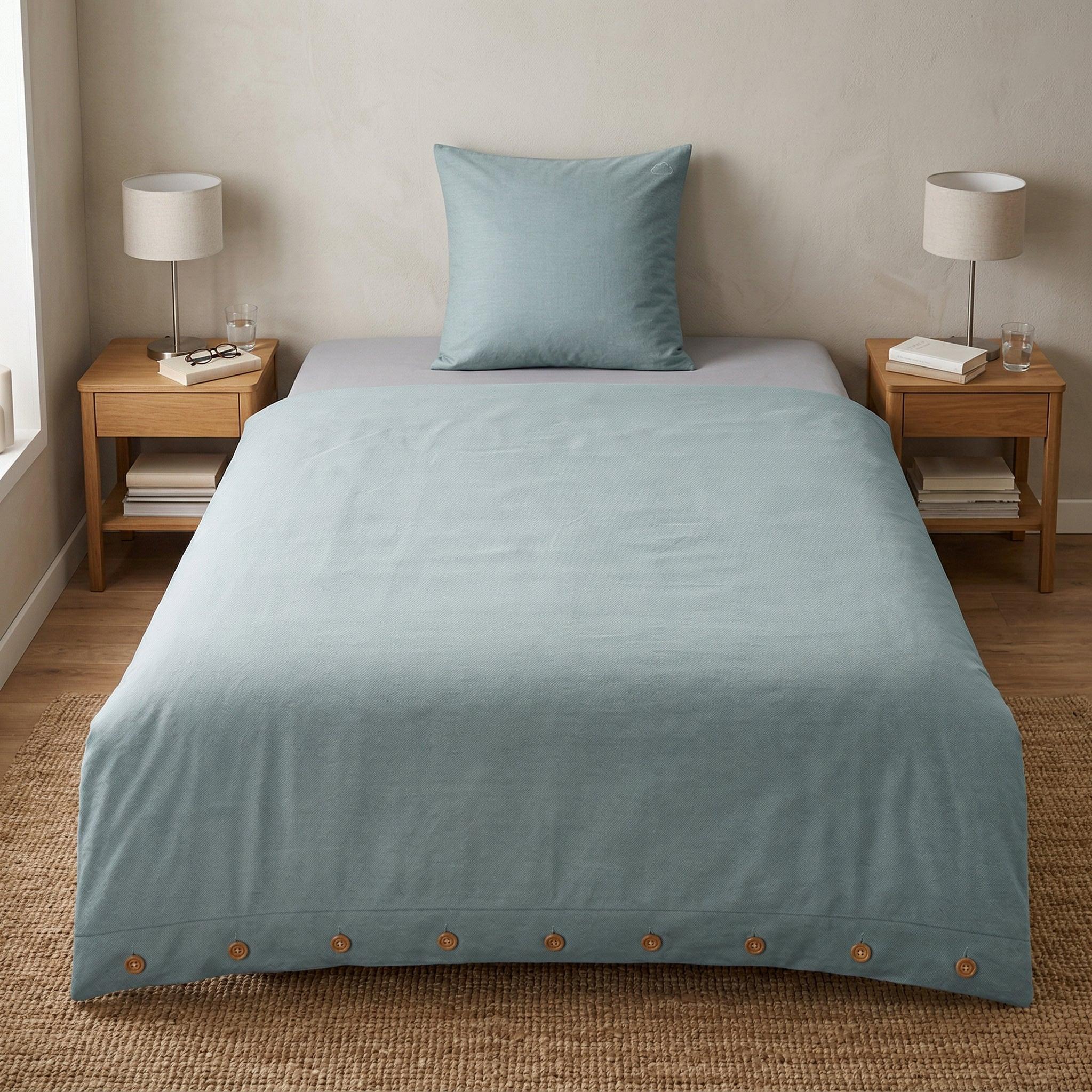 Hellblaue Bettwäsche mit Kissen auf gemachtem Bett im Schlafzimmer.