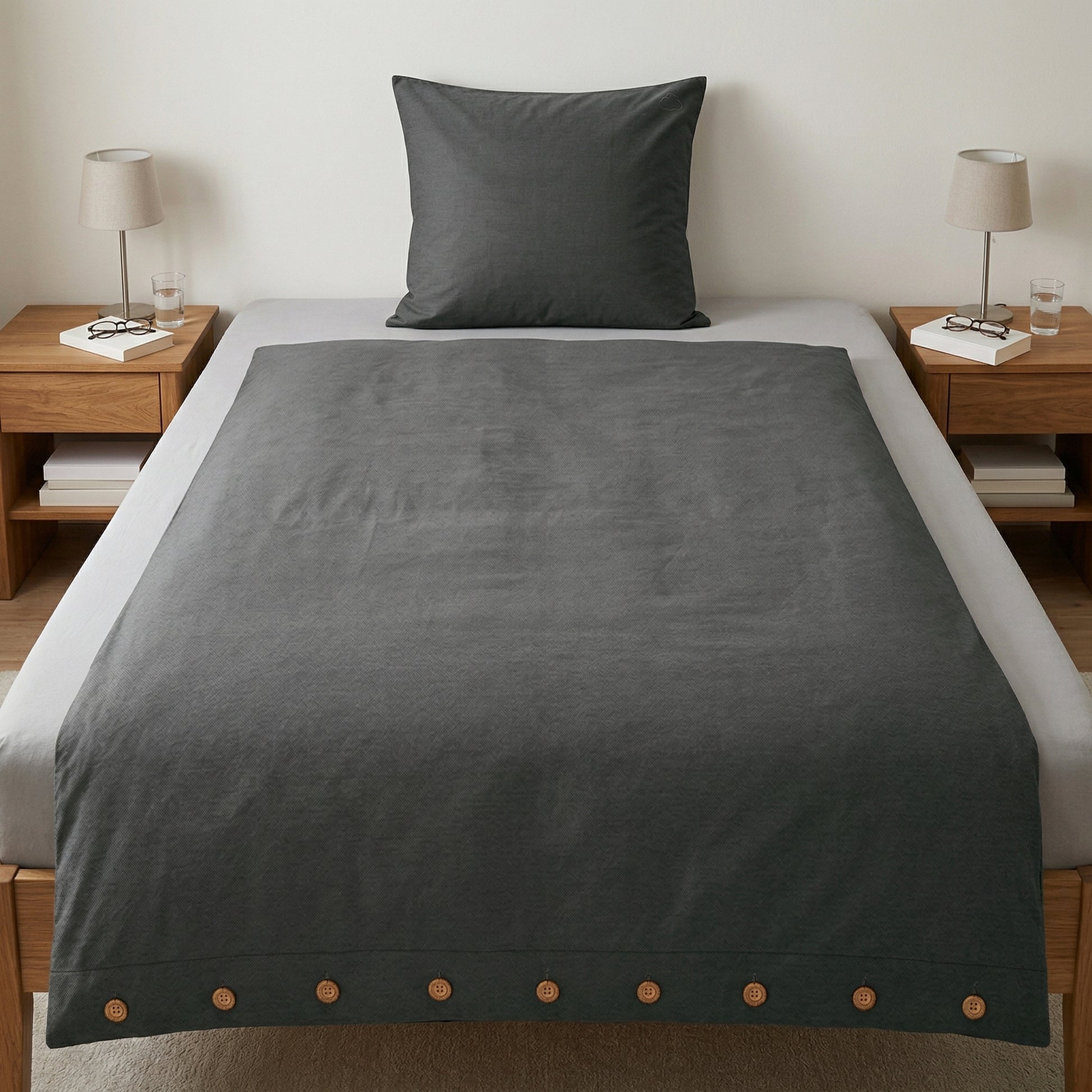Anthrazitfarbene Bettwäsche mit Knopfleiste auf modernem Bett.