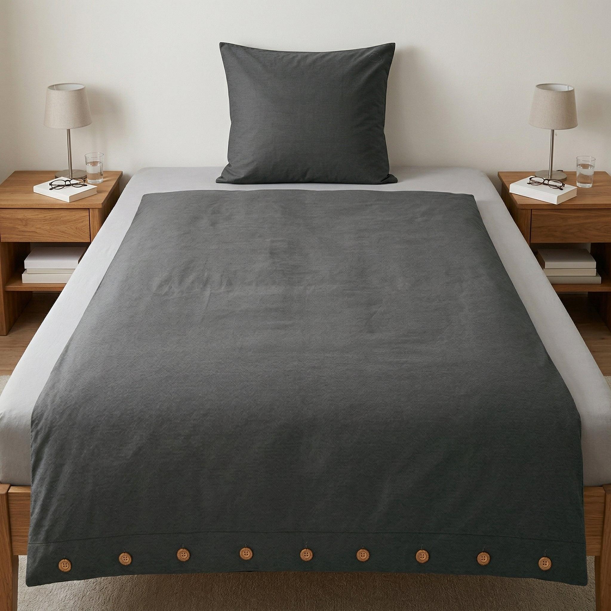 Anthrazitfarbene Bettwäsche mit Knopfleiste auf modernem Bett.
