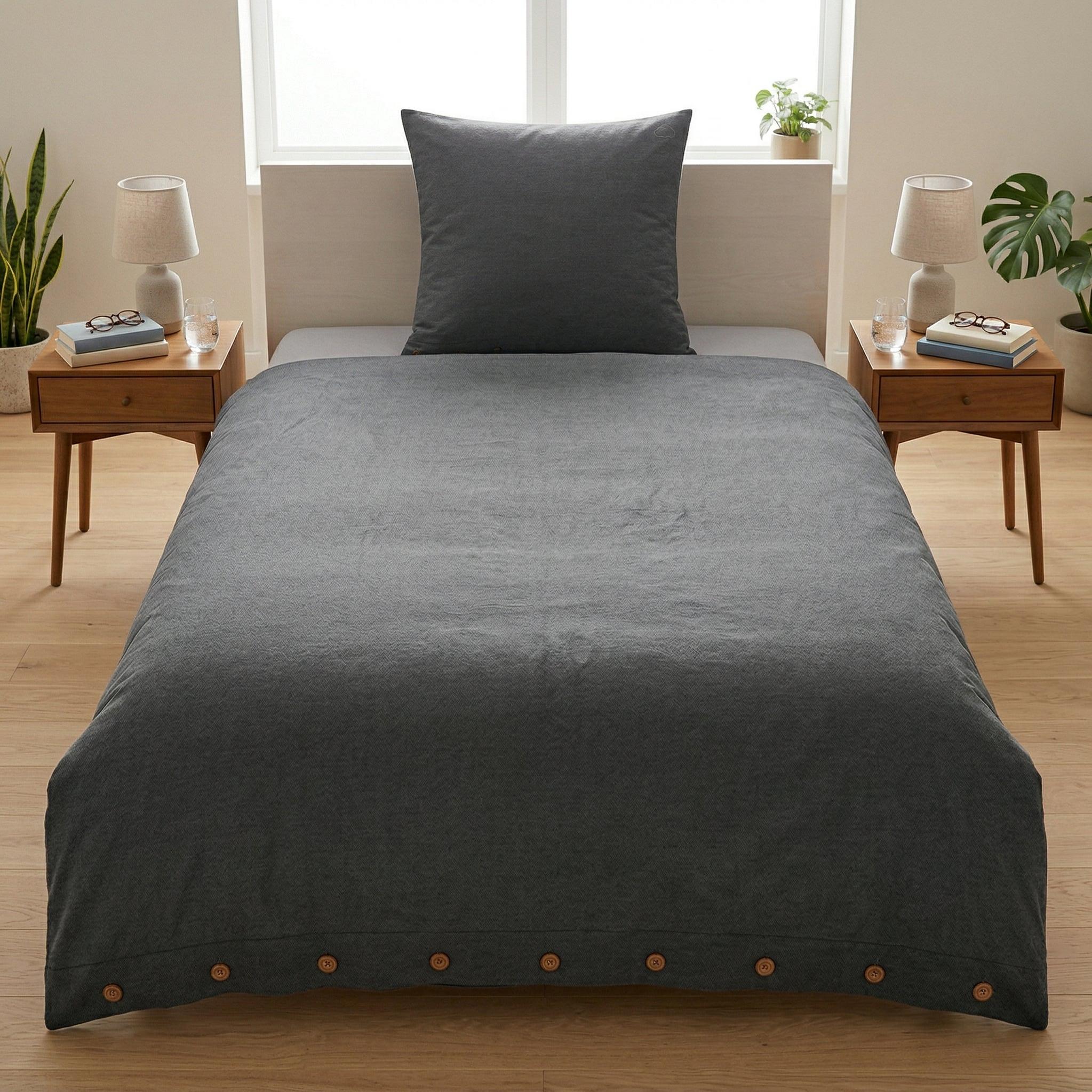 Dunkelgraue Bettwäsche mit Kissen auf modern gemachtem Bett.