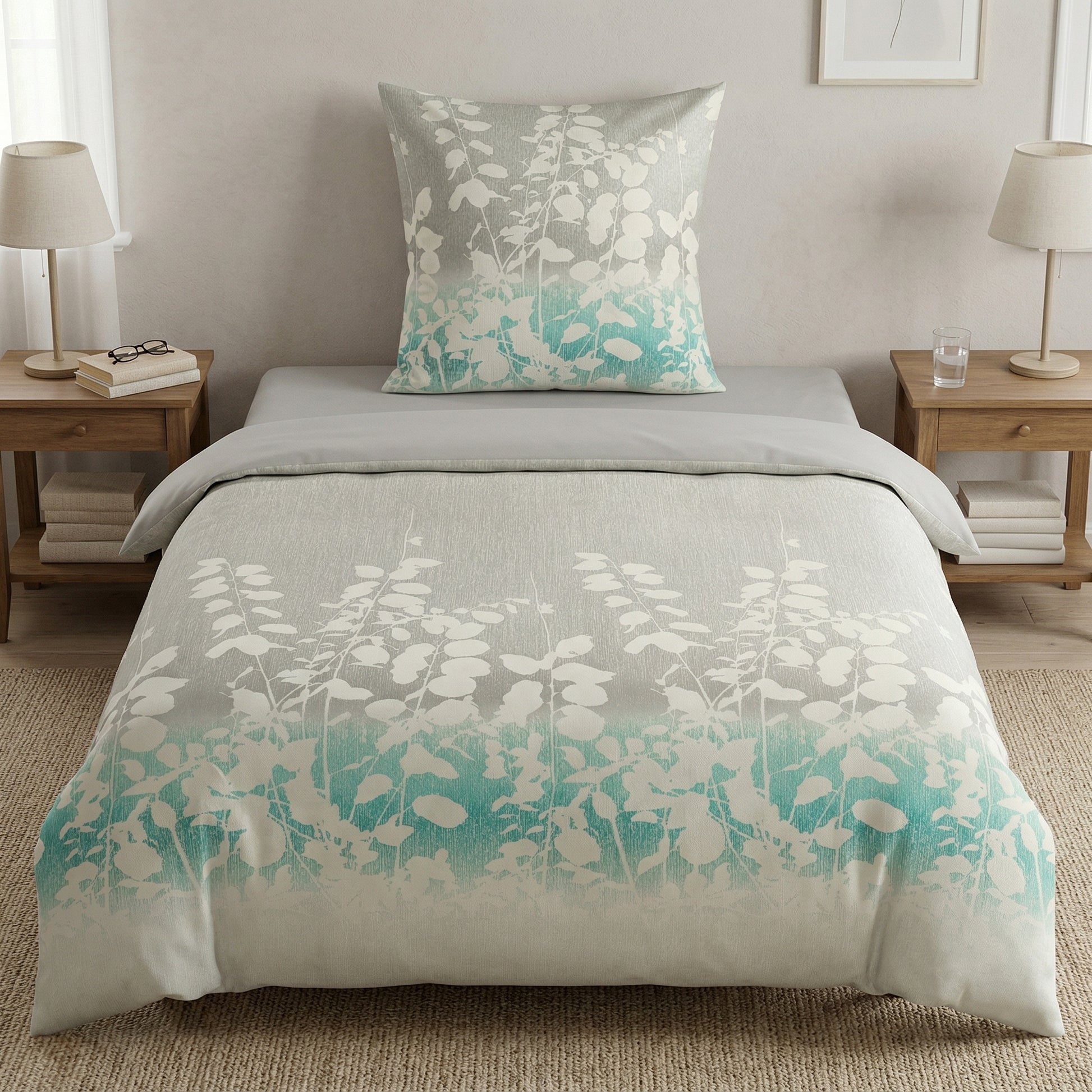 Bettwäsche mit weißem Blattmuster in Grau und Türkis auf Bett.