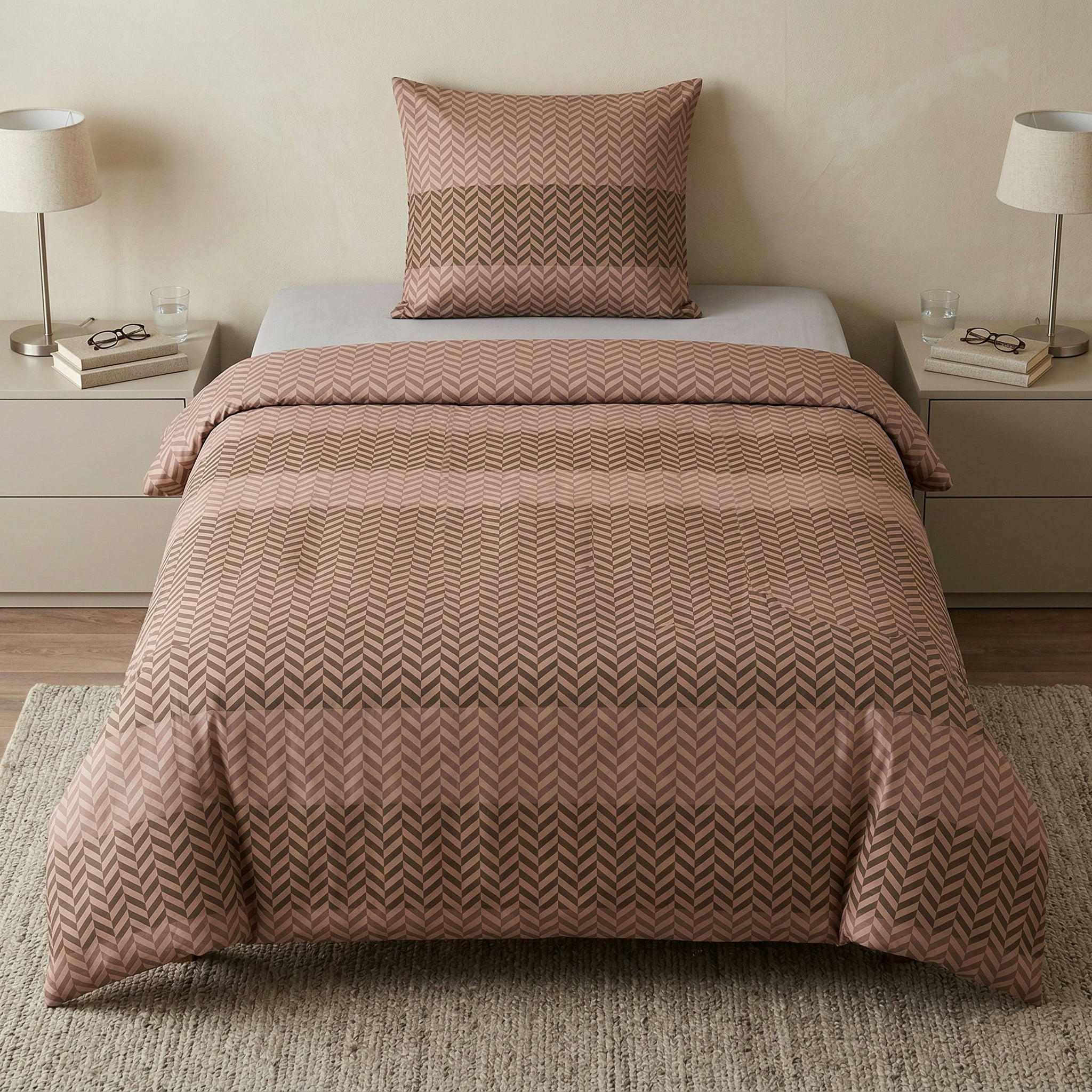 Rosé Bettwäsche im Zickzackmuster auf Bett zwischen zwei Nachttischen.