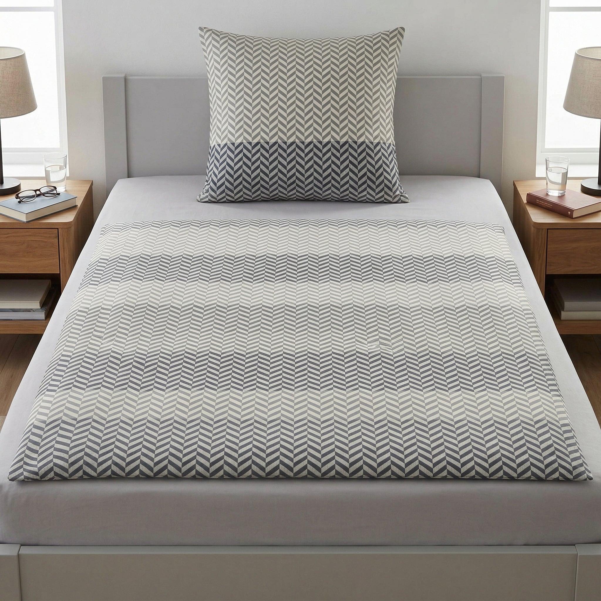 Graue Bettwäsche mit Fischgrätmuster auf modernem Bett.