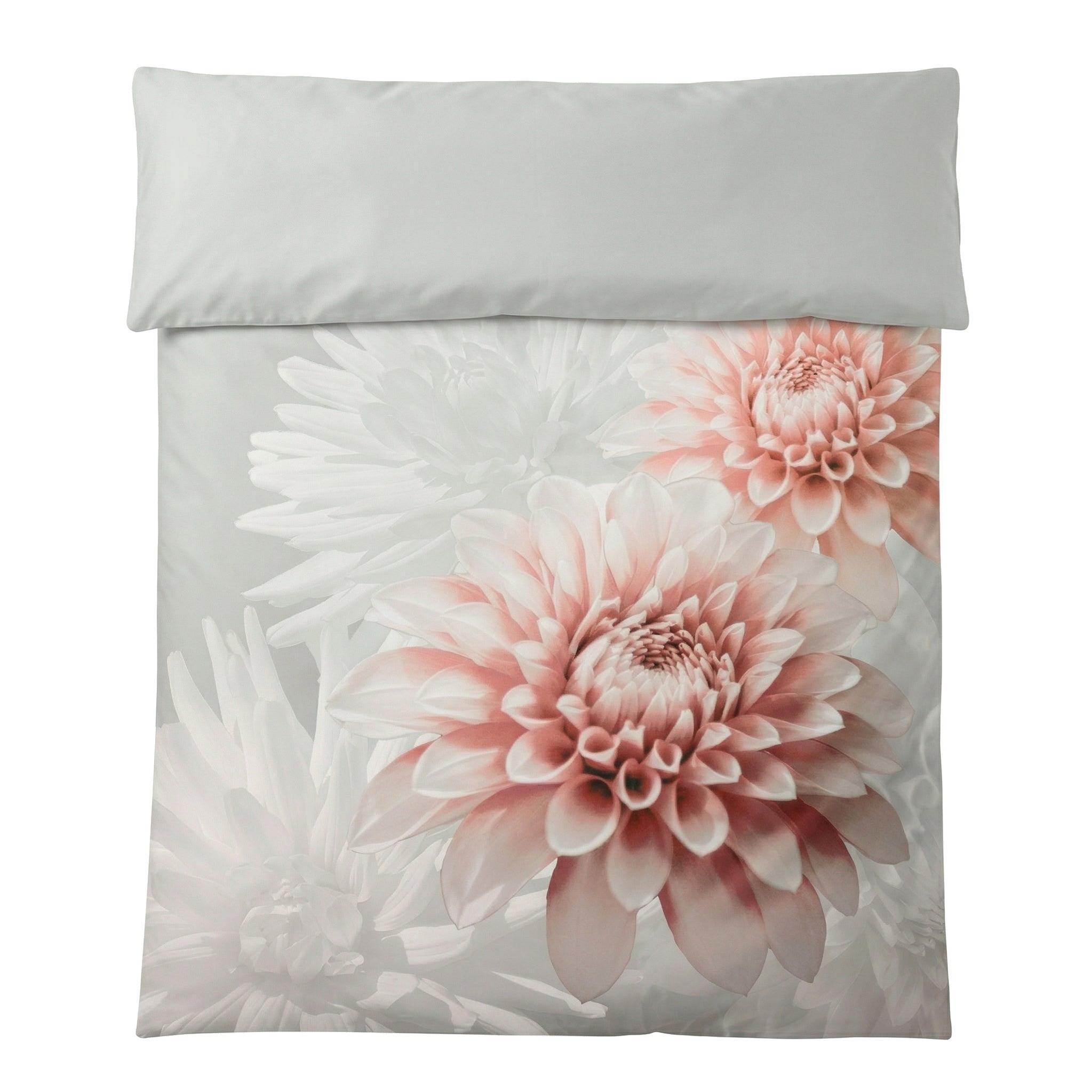 Graue Bettwäsche mit großen Blüten in zartem Rosa und Weiß.