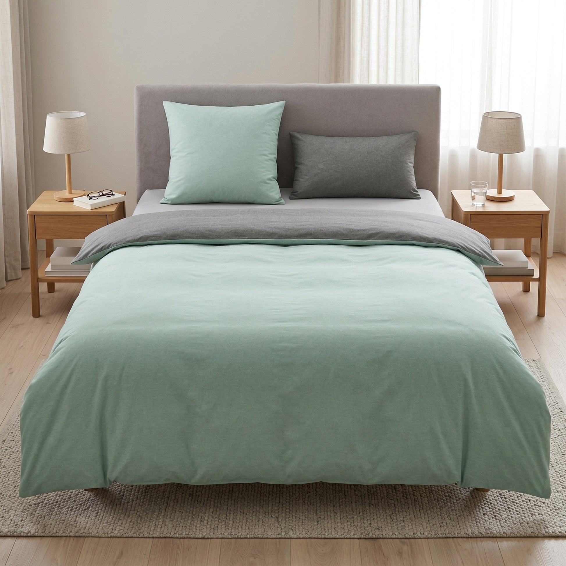 Mintgrüne Bettwäsche mit grauen Kissen in hellem Schlafzimmer.