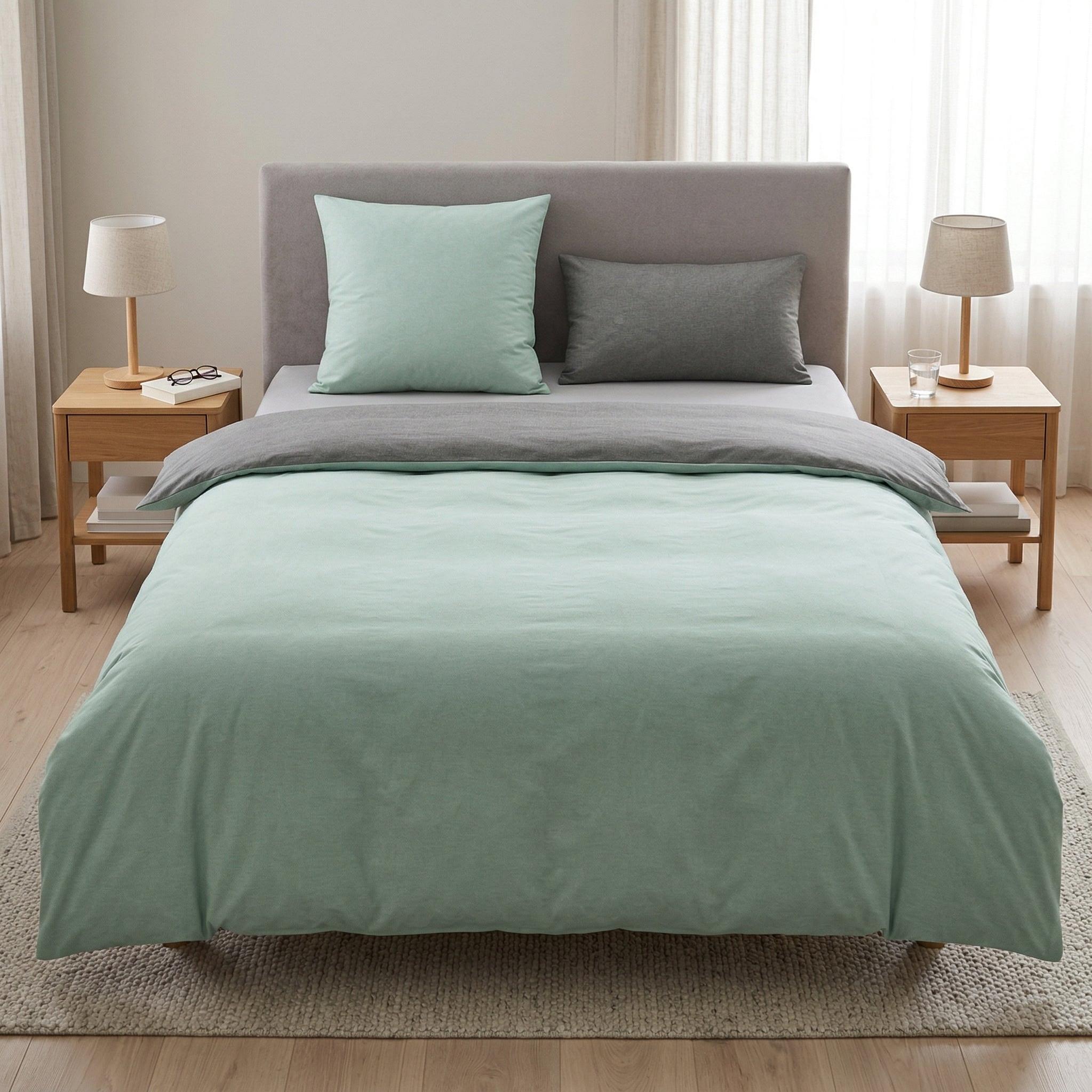 Mintgrüne Bettwäsche mit grauen Kissen in hellem Schlafzimmer.