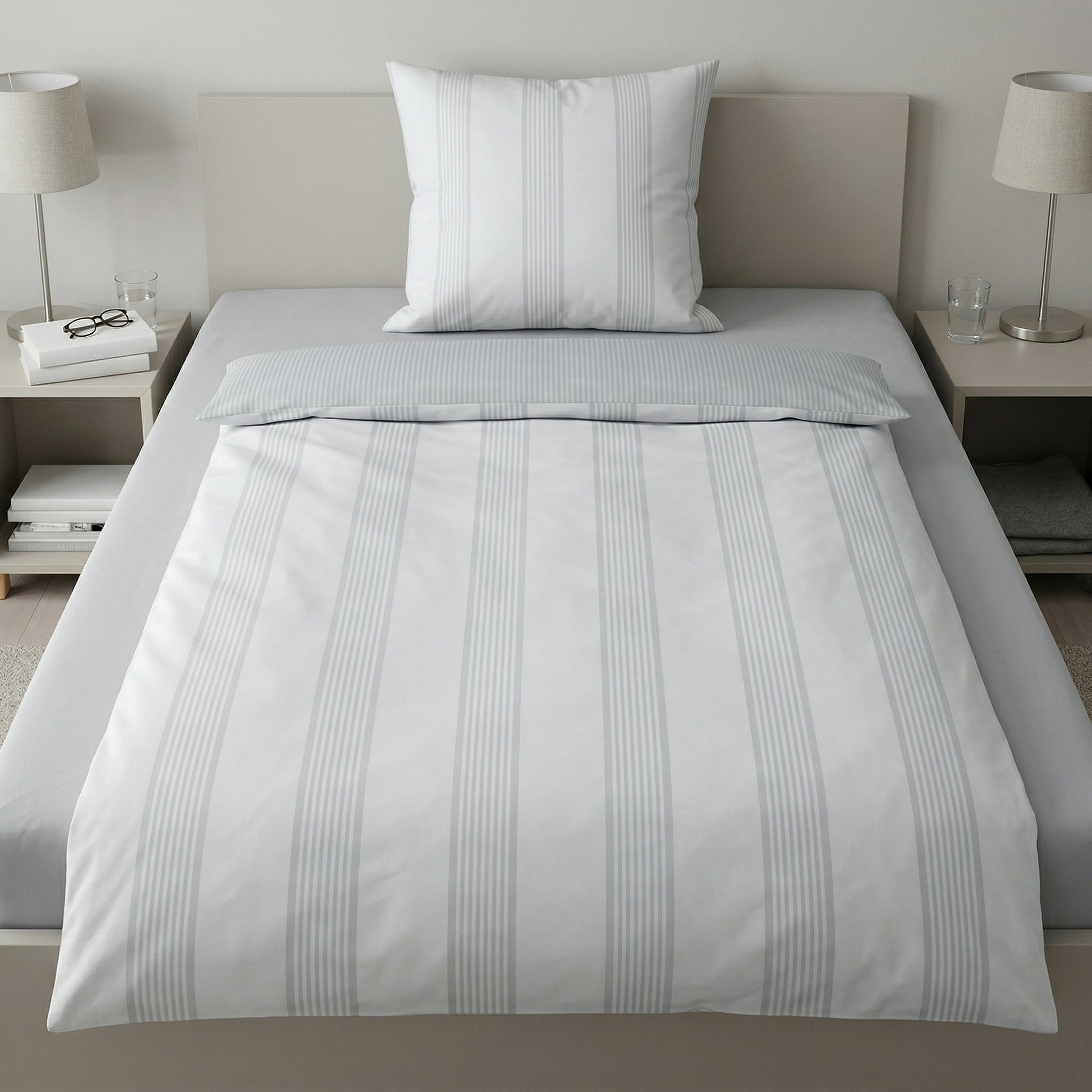Gestreifte Bettwäsche in Weiß-Grau auf Bett, Nachttische mit Lampen.