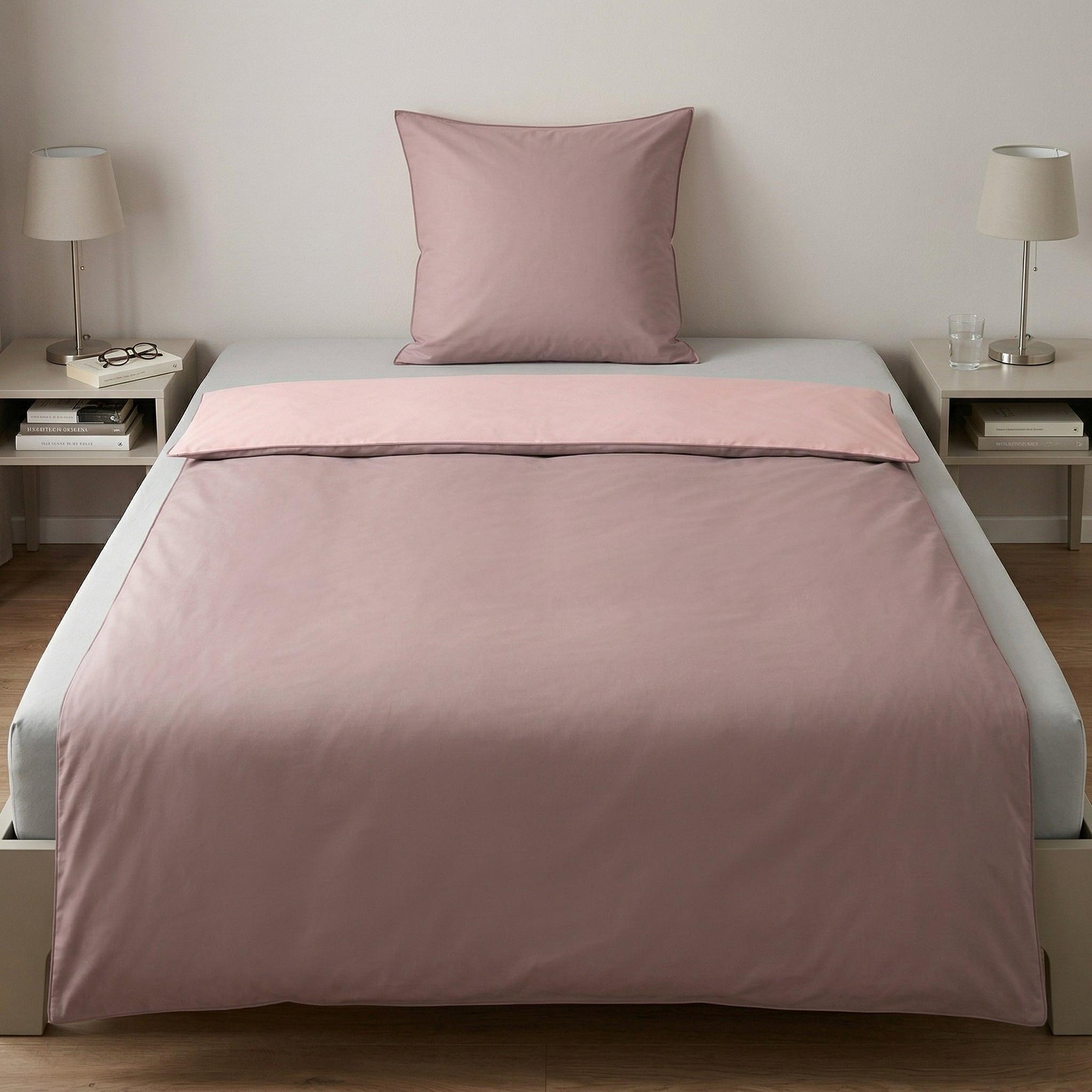 Rosa Bettwäsche-Set auf gemachtem Bett mit Kissen.