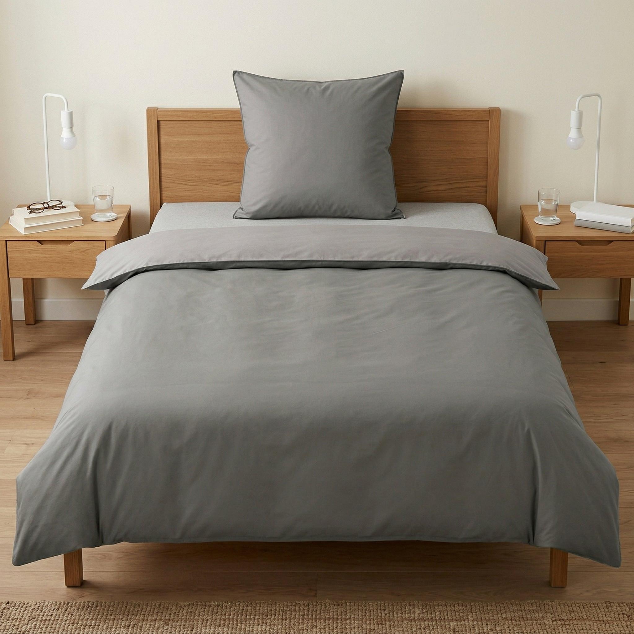 Graue Bettwäsche auf Holzbetten in minimalistischem Schlafzimmer.