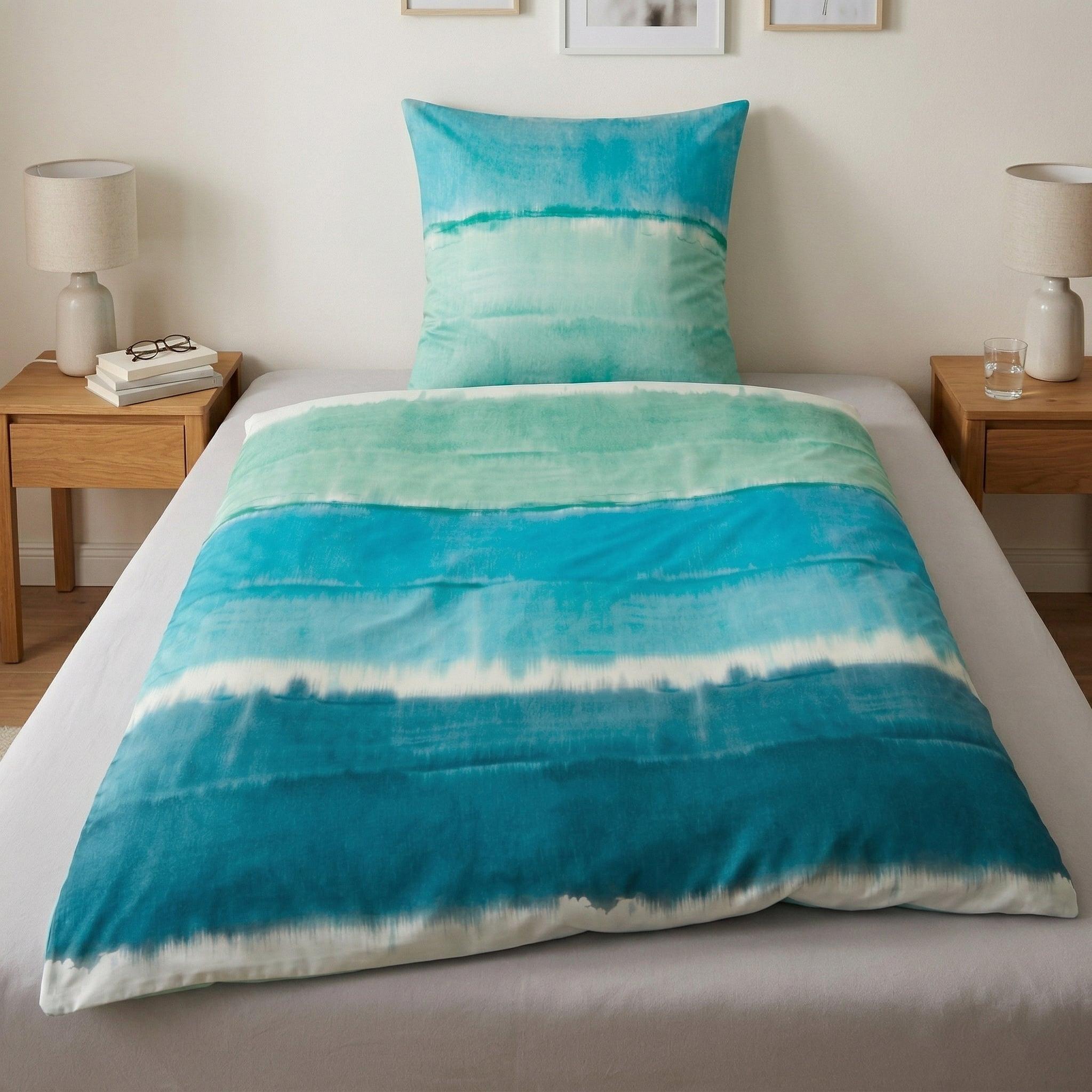 Bettwäsche mit blauem Aquarellmuster auf einem Einzelbett.