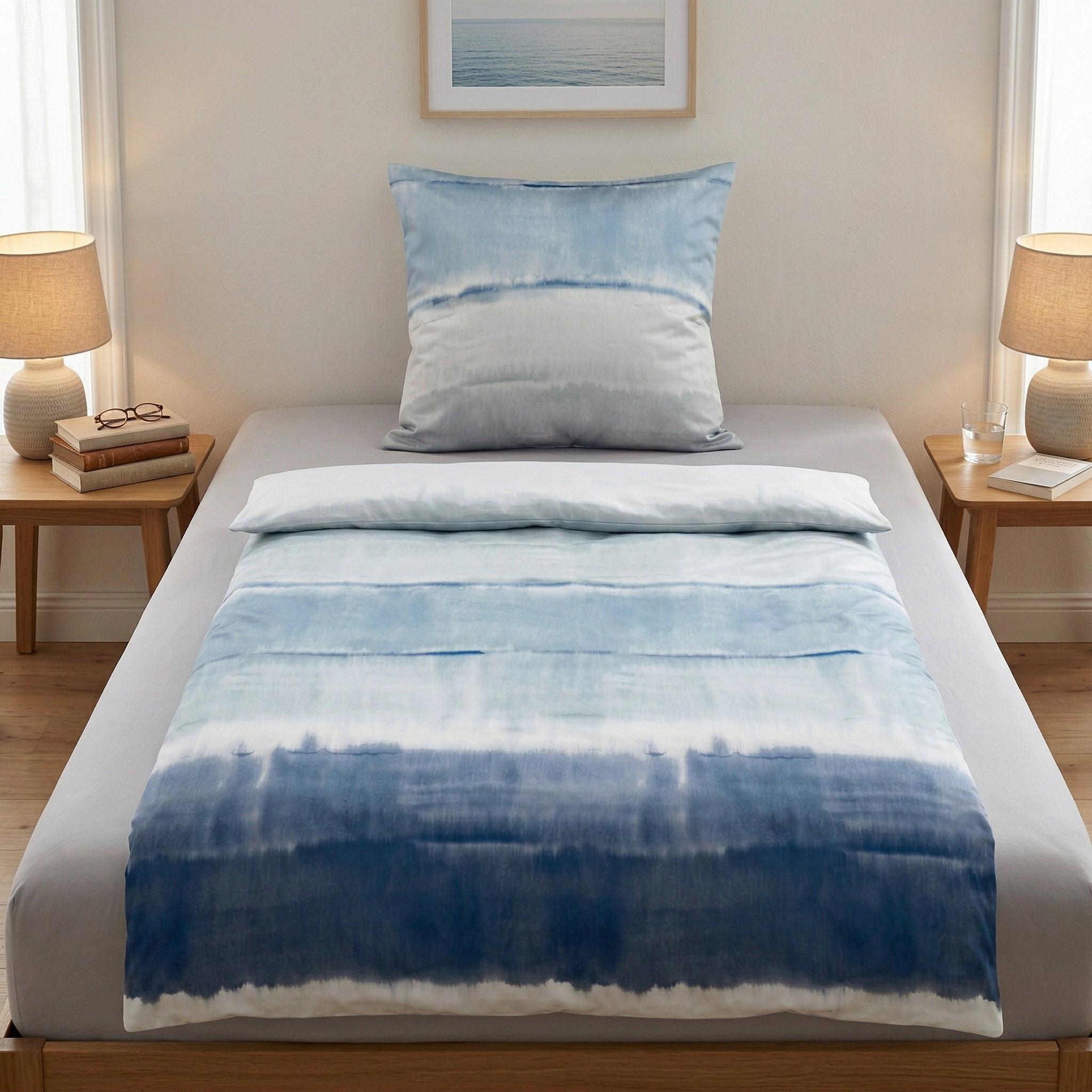 Blau-weiße Bettwäsche im Batiklook auf einem modern gedeckten Bett.