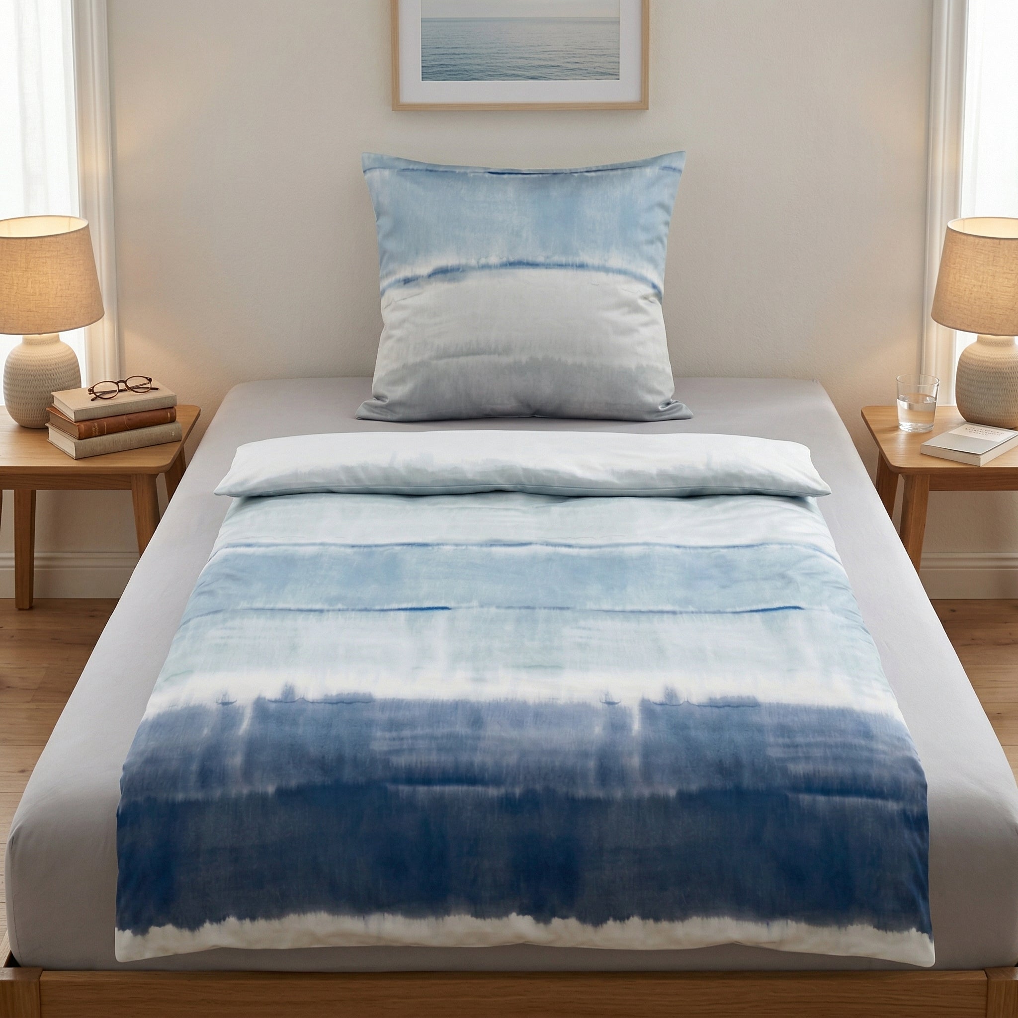 Blau-weiße Bettwäsche im Batiklook auf einem modern gedeckten Bett.