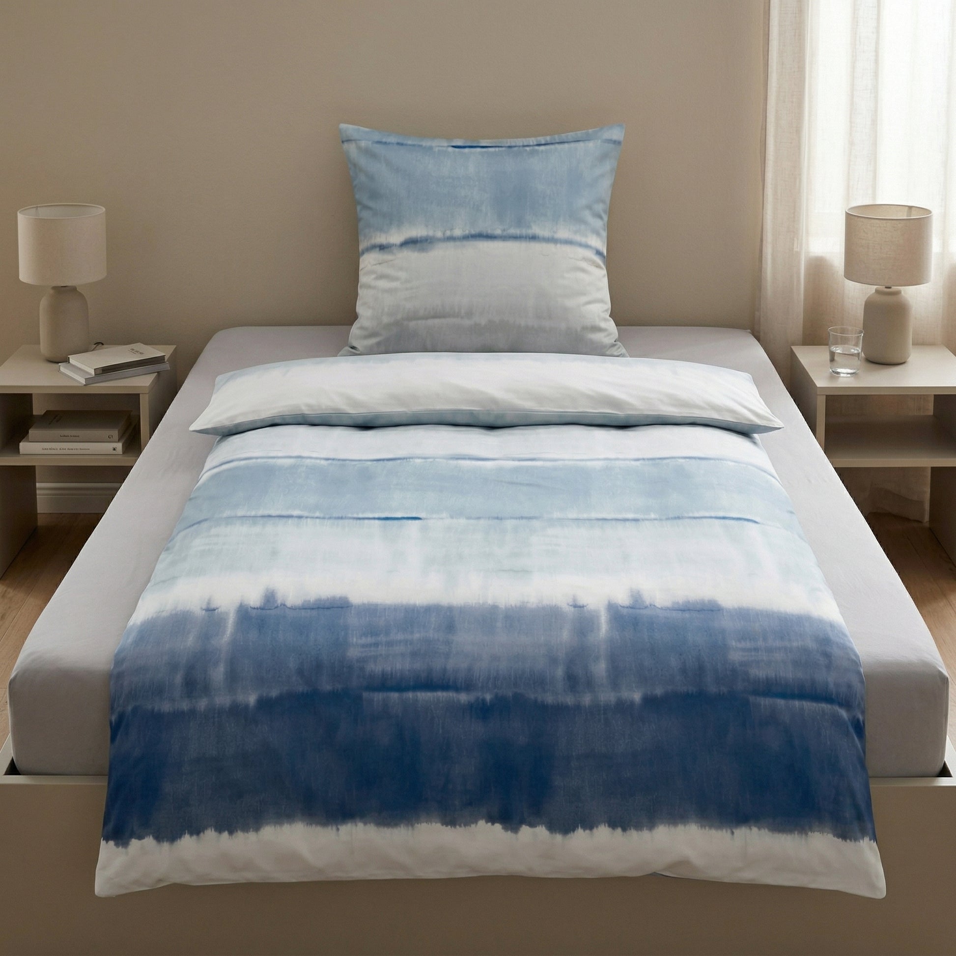 Blau-weiße Batik-Bettwäsche auf einem schlicht dekorierten Bett.