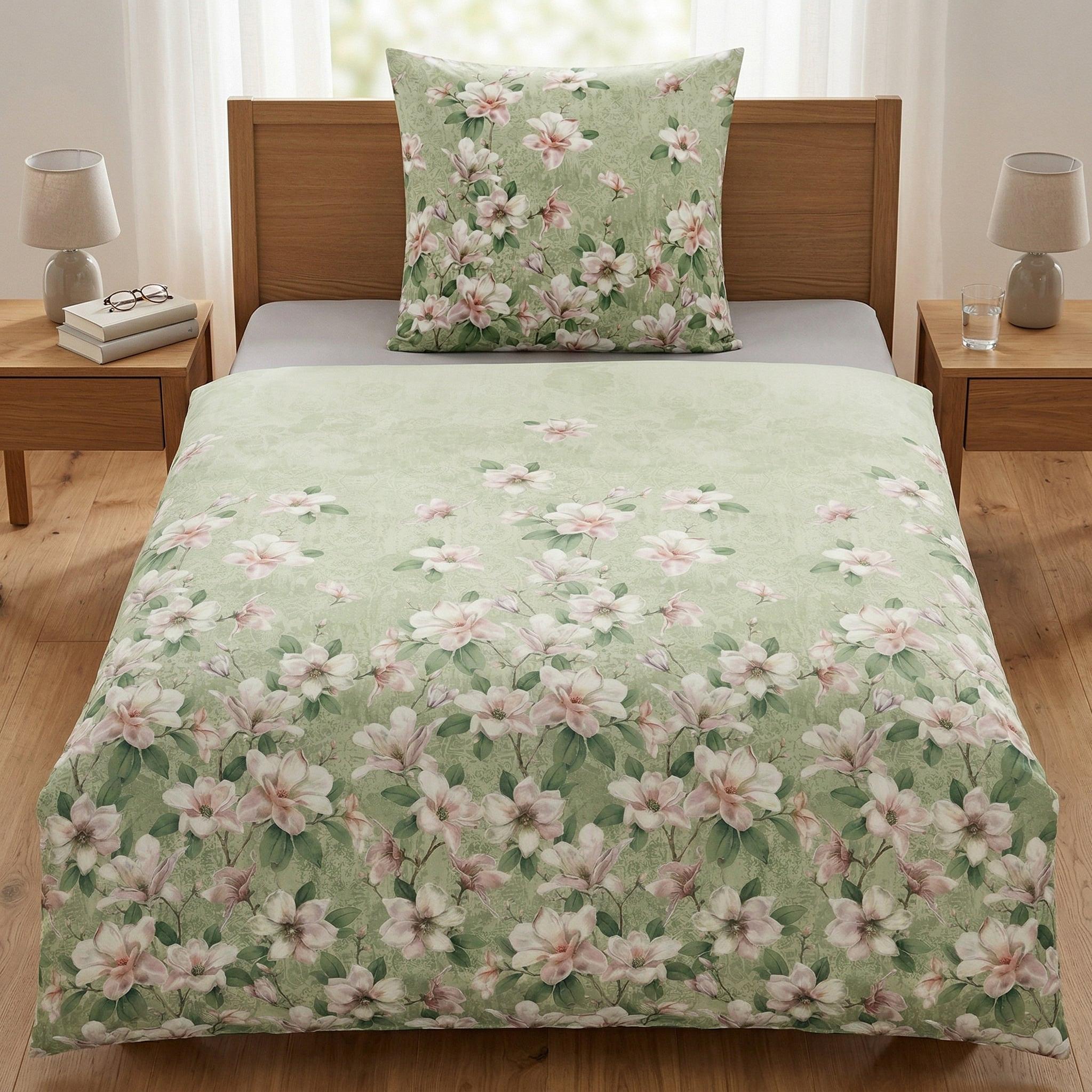 Grüne Bettwäsche mit rosa Blütenmuster auf einem Holzbett.