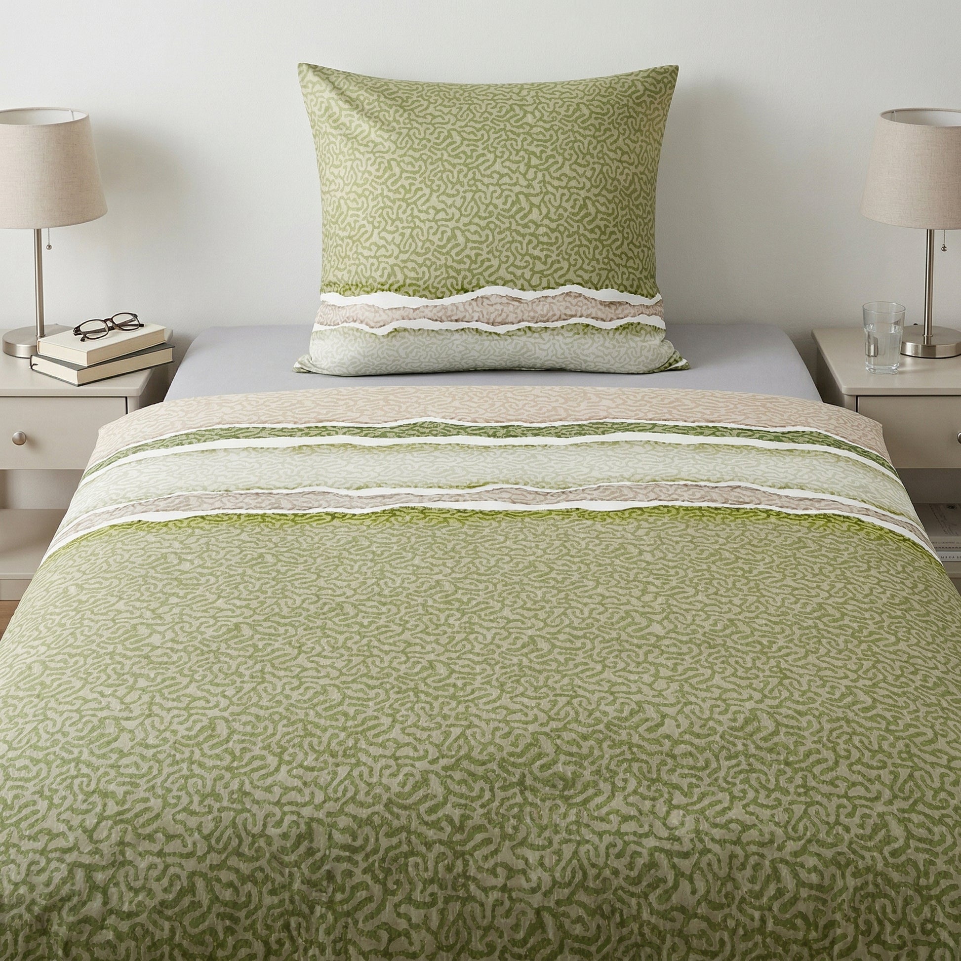 Grün-beige Bettwäsche mit Muster auf einem modern gemachten Bett.