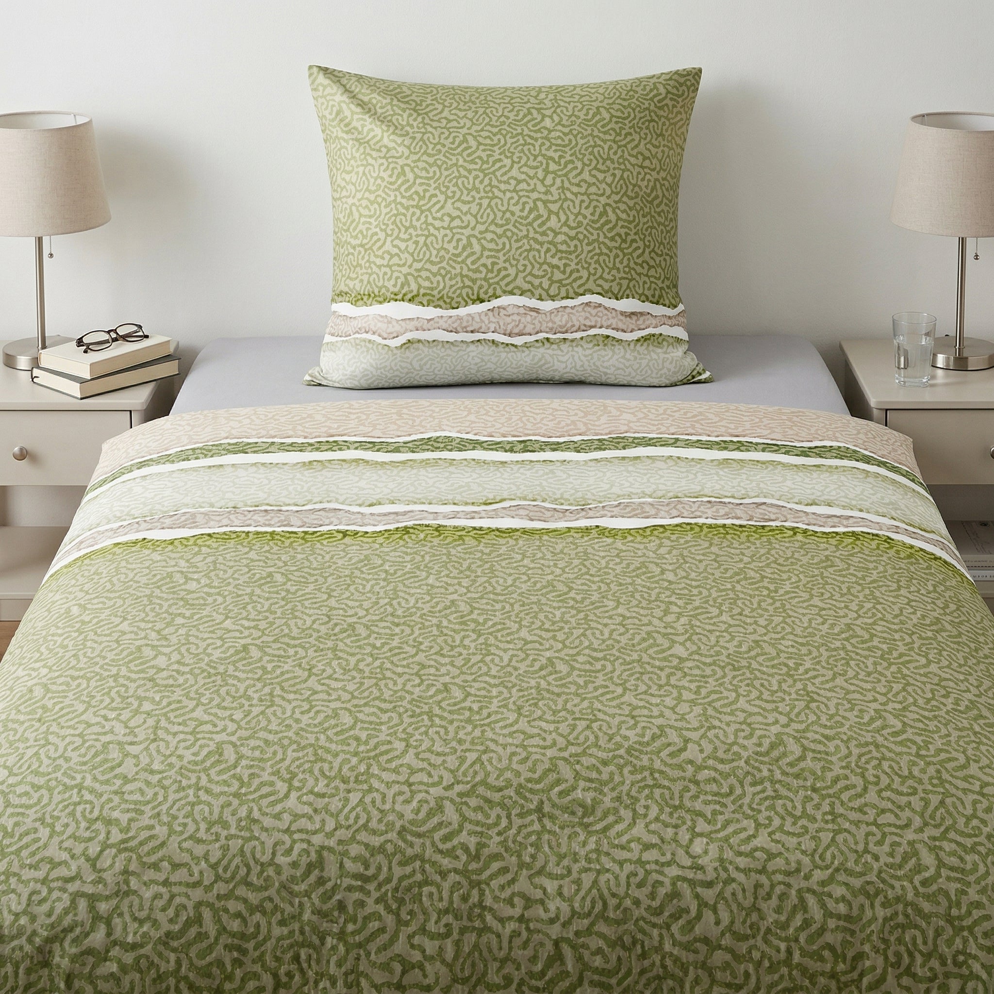 Grün-beige Bettwäsche mit Muster auf einem modern gemachten Bett.