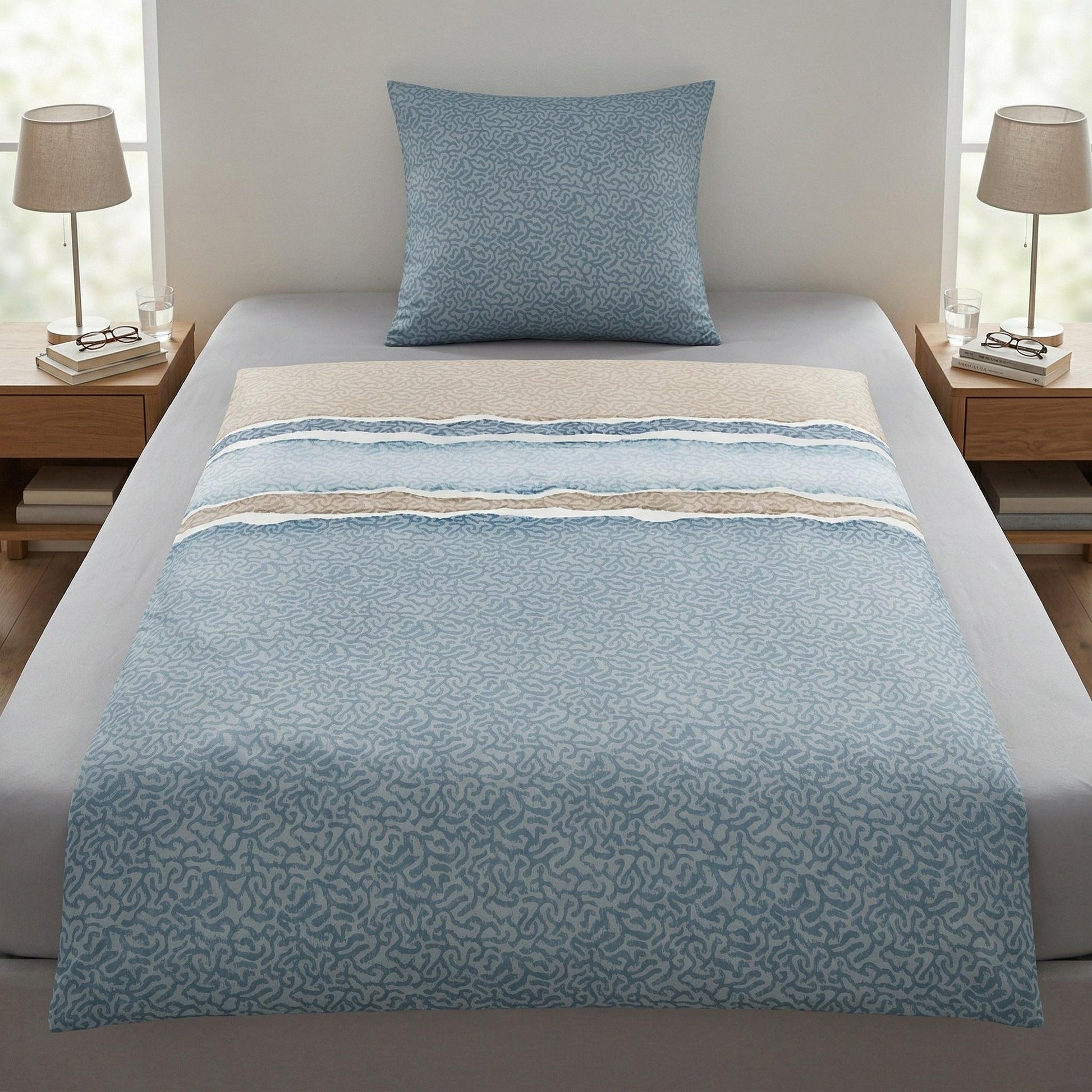 Blau-beige Bettwäsche mit Muster auf einem modern bezogenen Bett.