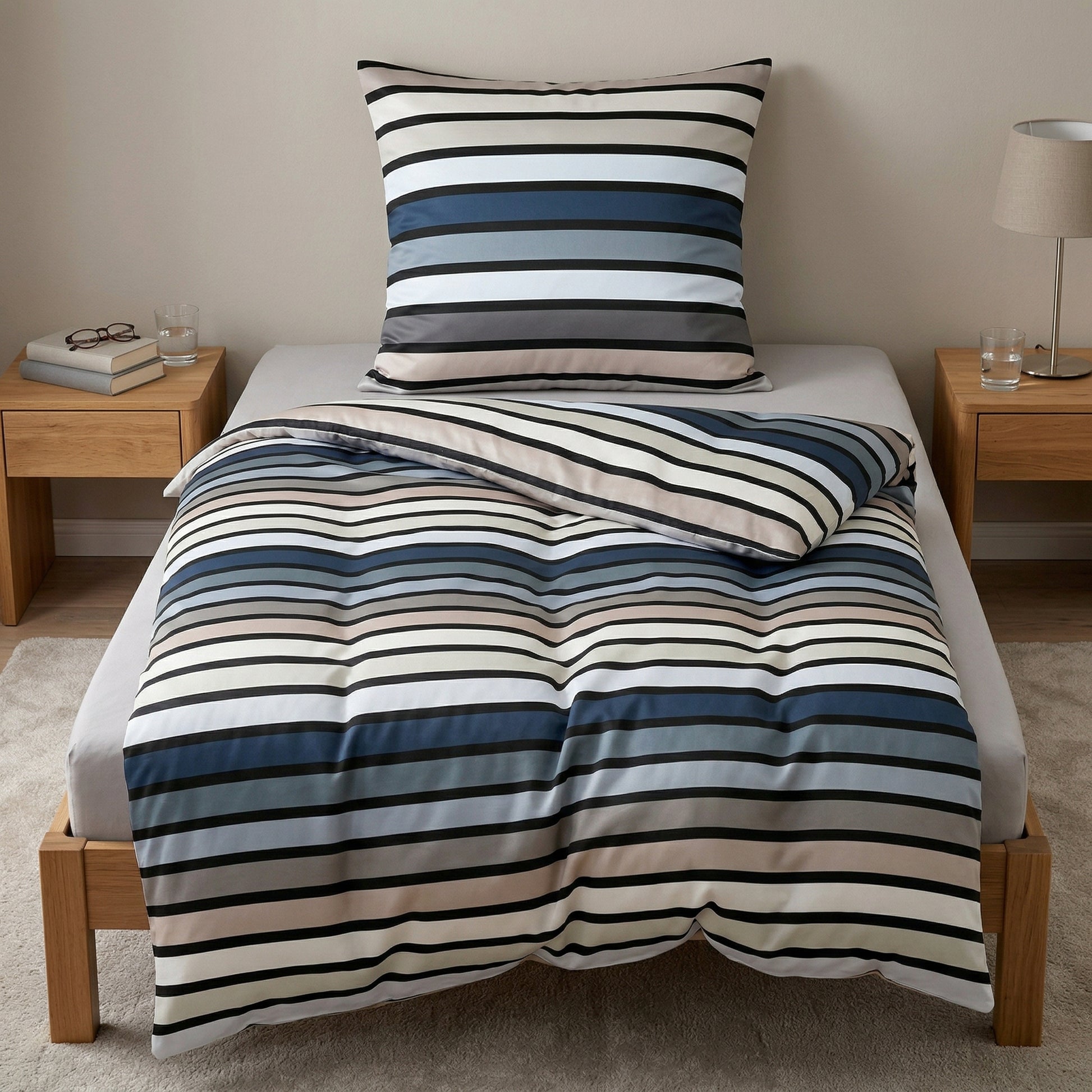 Gestreifte Bettwäsche in Blau, Grau und Weiß auf Bett.
