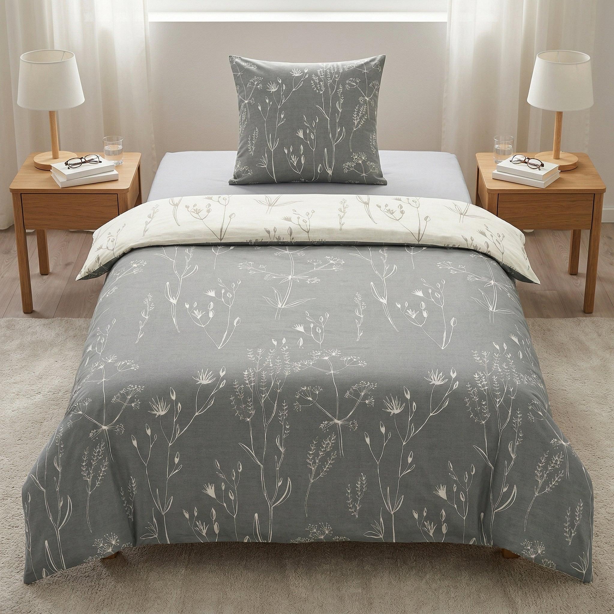 Graue Bettwäsche mit weißem Blumenmuster auf gemachtem Bett.