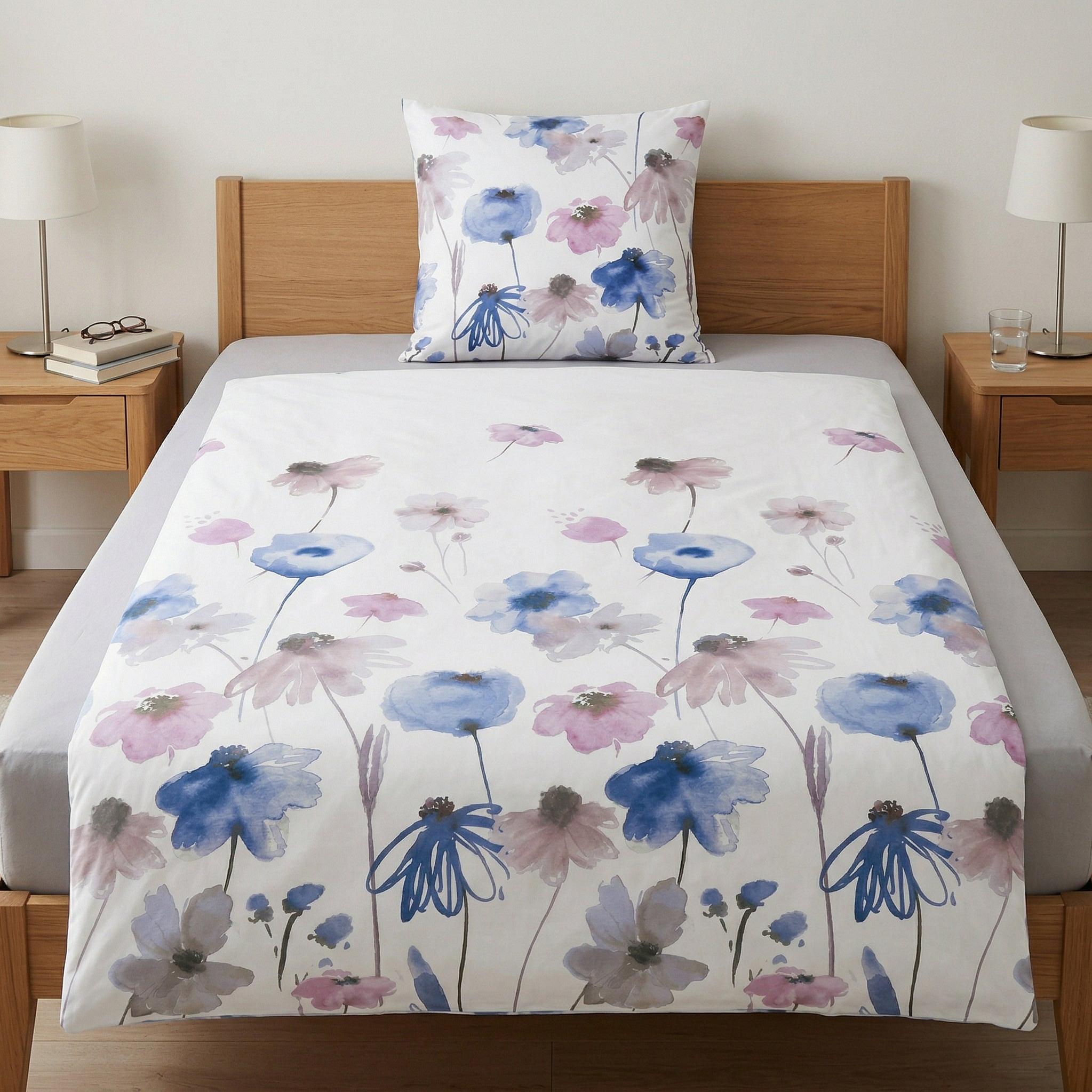 Weiße Bettwäsche mit blau-rosa Blumenmuster auf Holzbett.