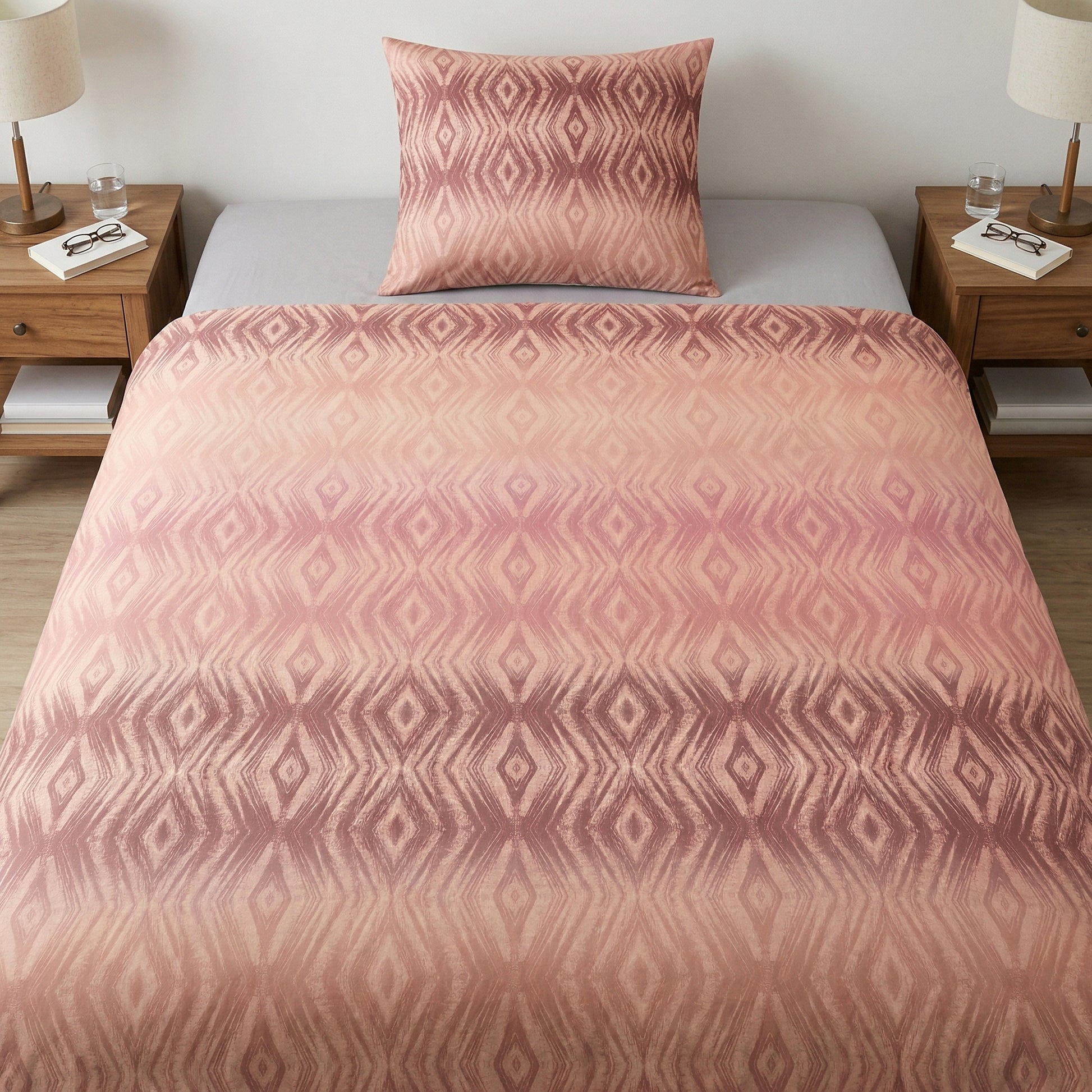 Rosa Bettwäsche mit geometrischem Muster auf gemachtem Bett.
