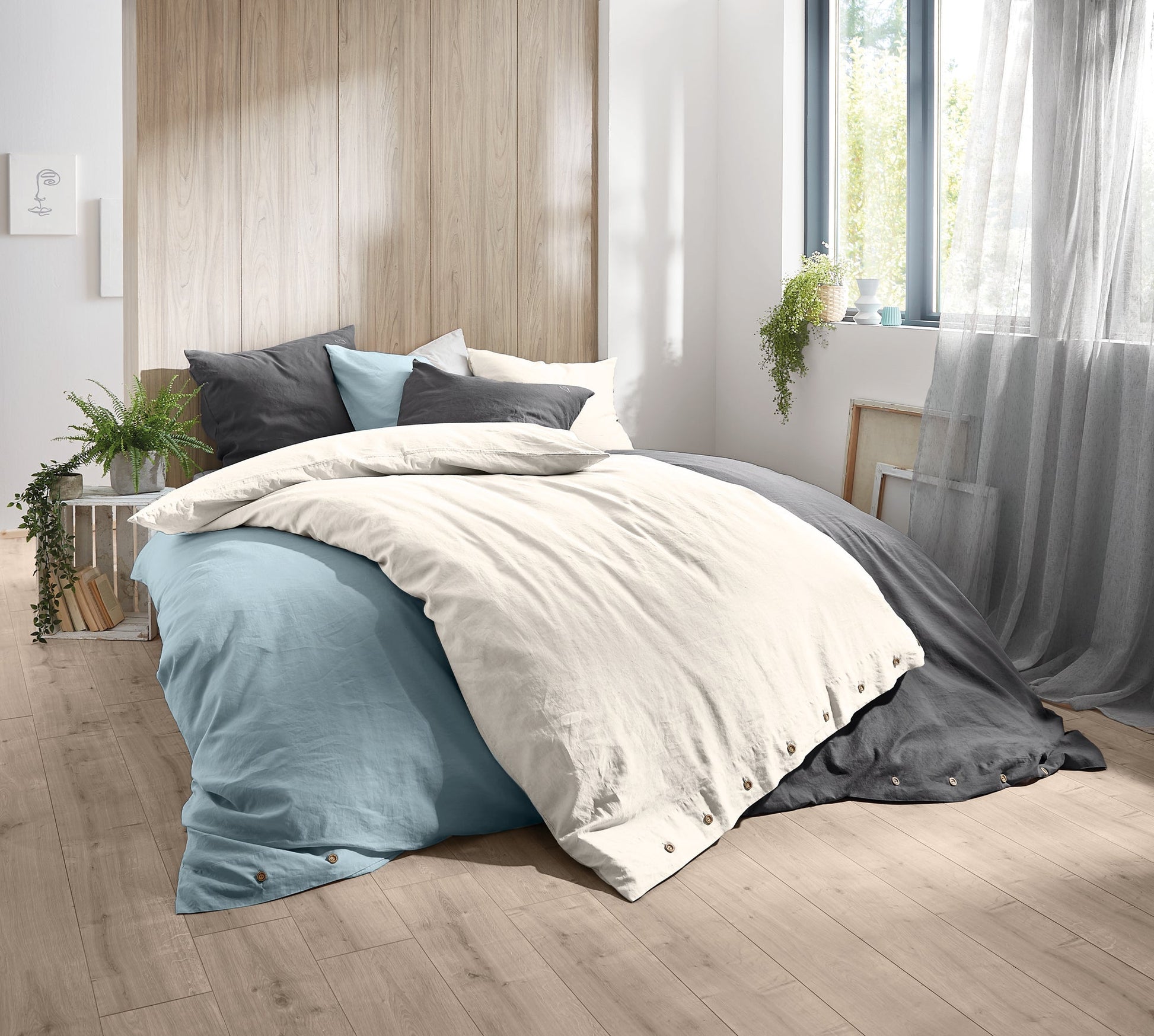 Modernes Bett mit mehrfarbiger Bettwäsche und Kissen im hellen Zimmer