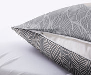 Nahaufnahme eines grauen Kopfkissens mit Blattmuster und Reißverschluss