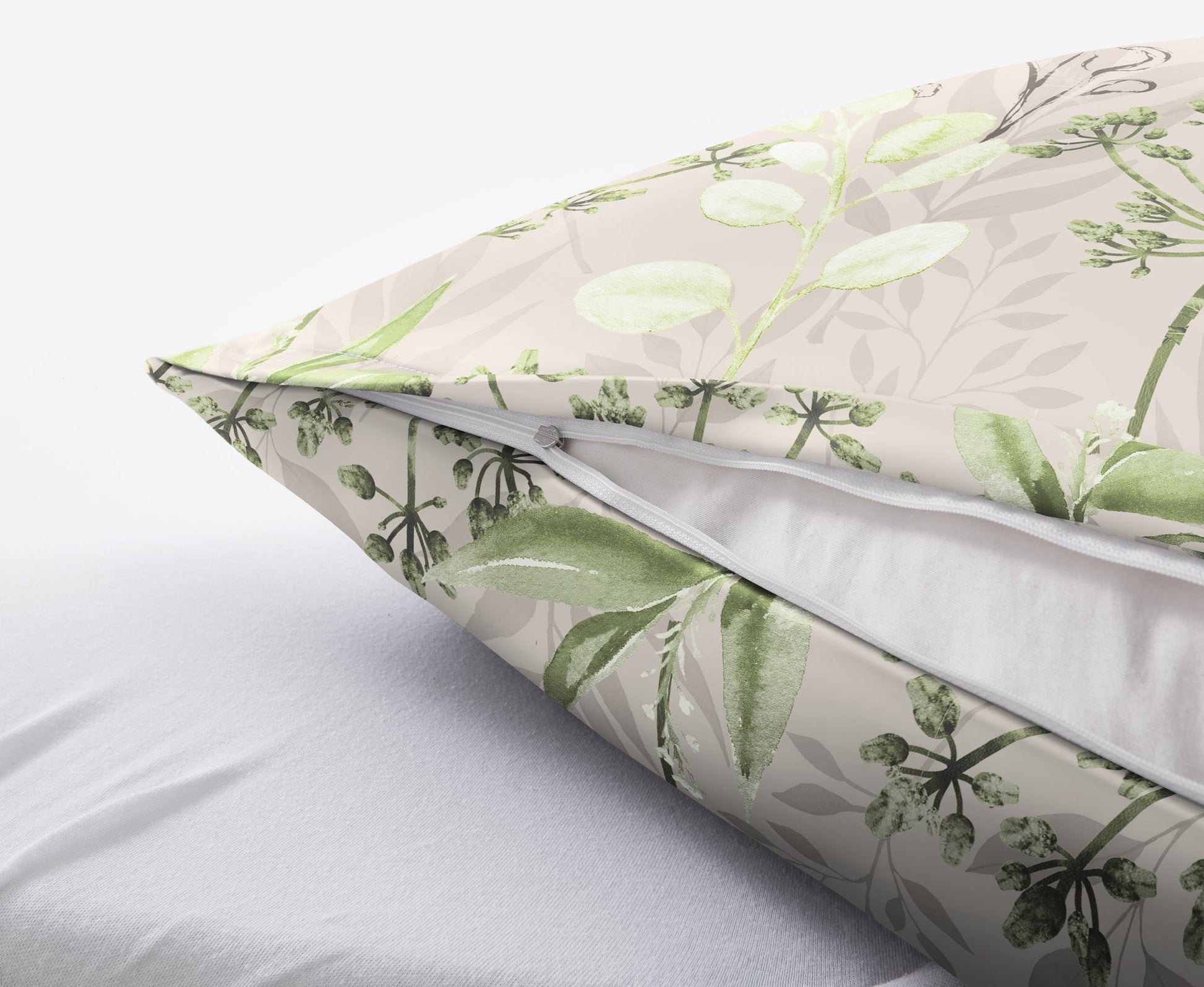Kissen mit grünem Blattmuster und sichtbarem Reißverschluss auf Bett