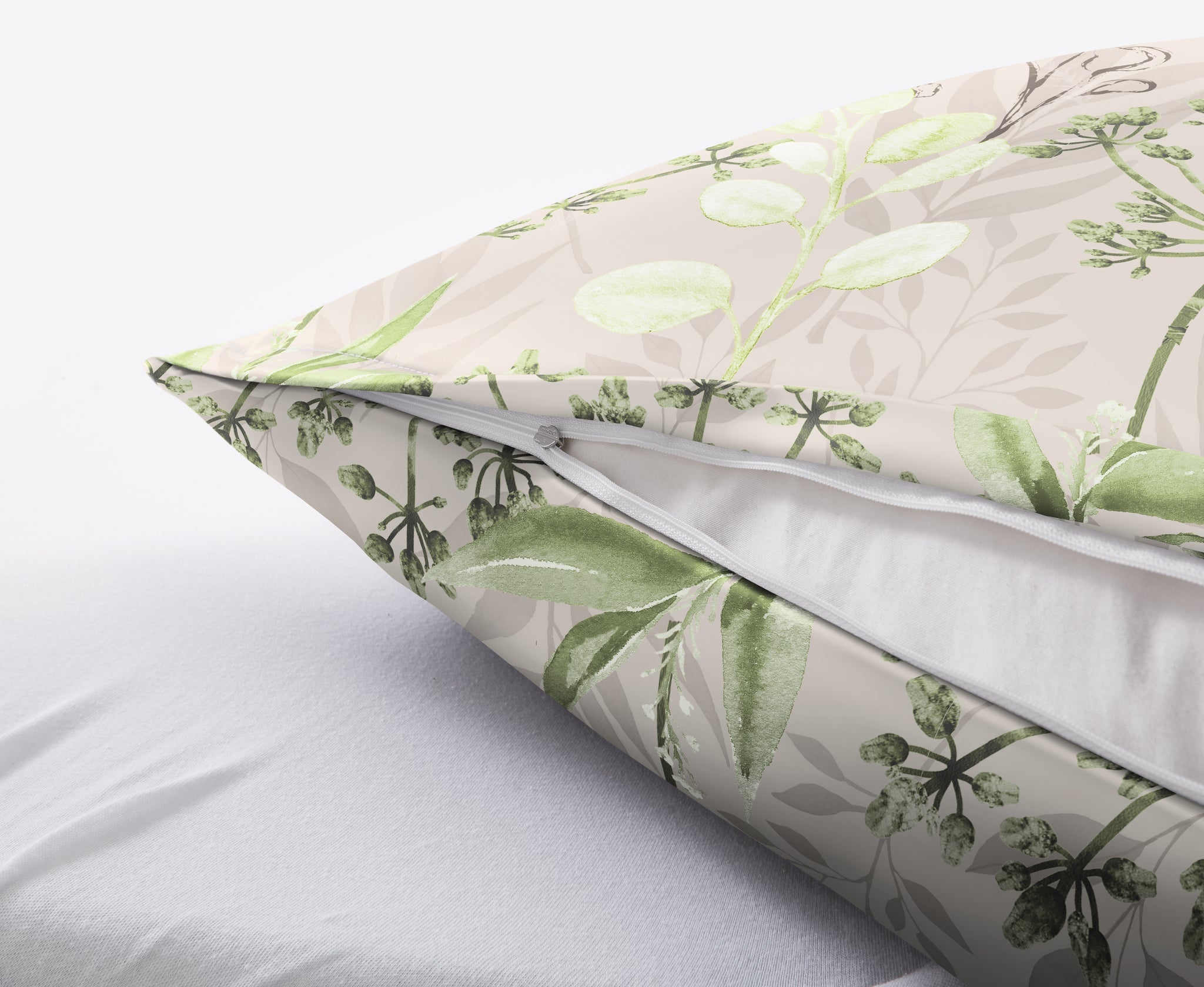 Kissen mit grünem Blattmuster und sichtbarem Reißverschluss auf Bett