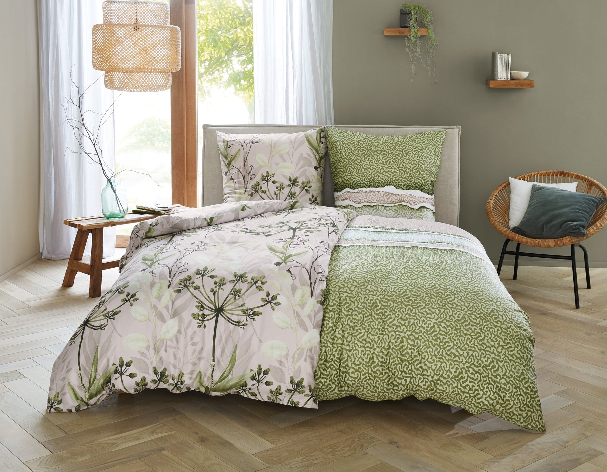 Doppelbett mit grün-gemusterter Bettwäsche und floraler Decke in Naturtönen
