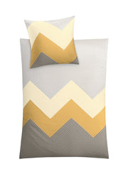 Bettwäsche Satin LYKKE Goldgelb 155x220 und 80x80 cm mit Zickzackmuster liegt glatt ausgebreitet.