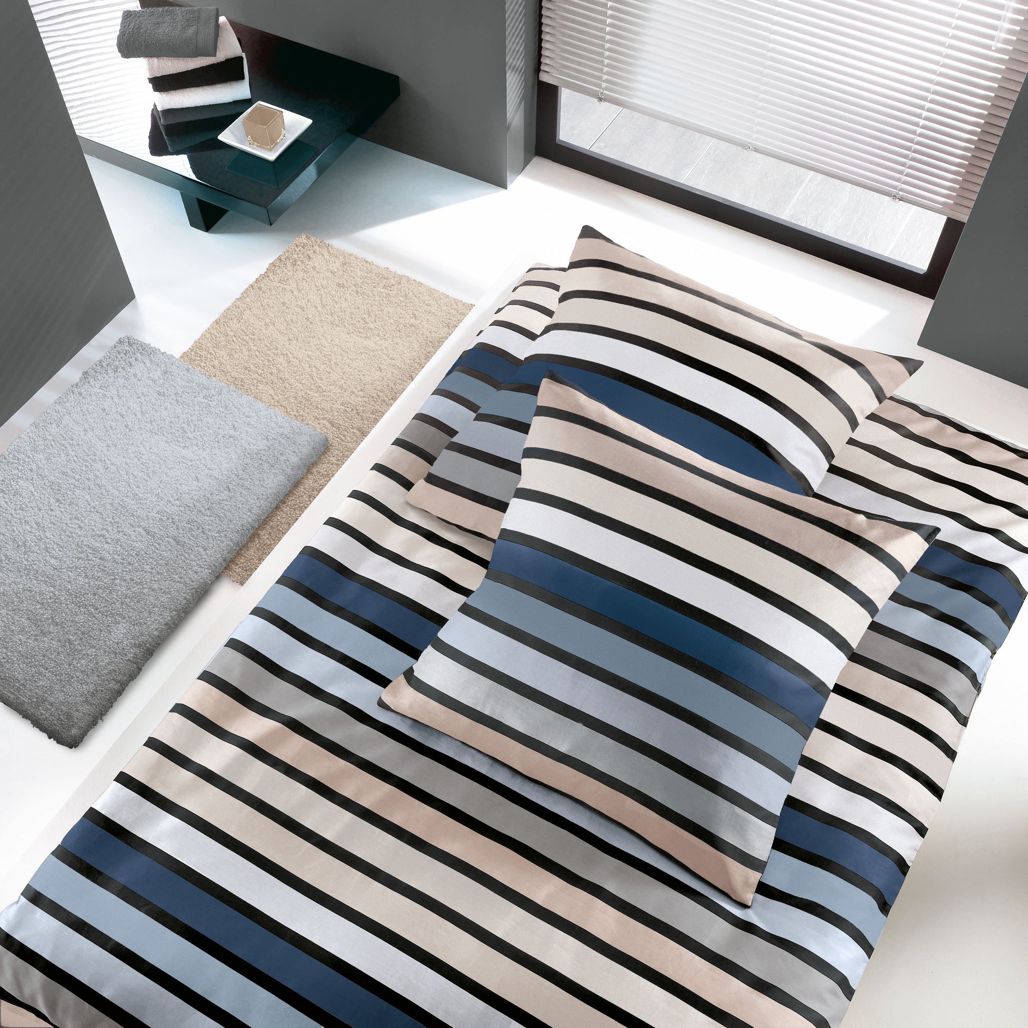 Bett mit gestreifter Bettwäsche in Beige, Blau, Grau und Weiß