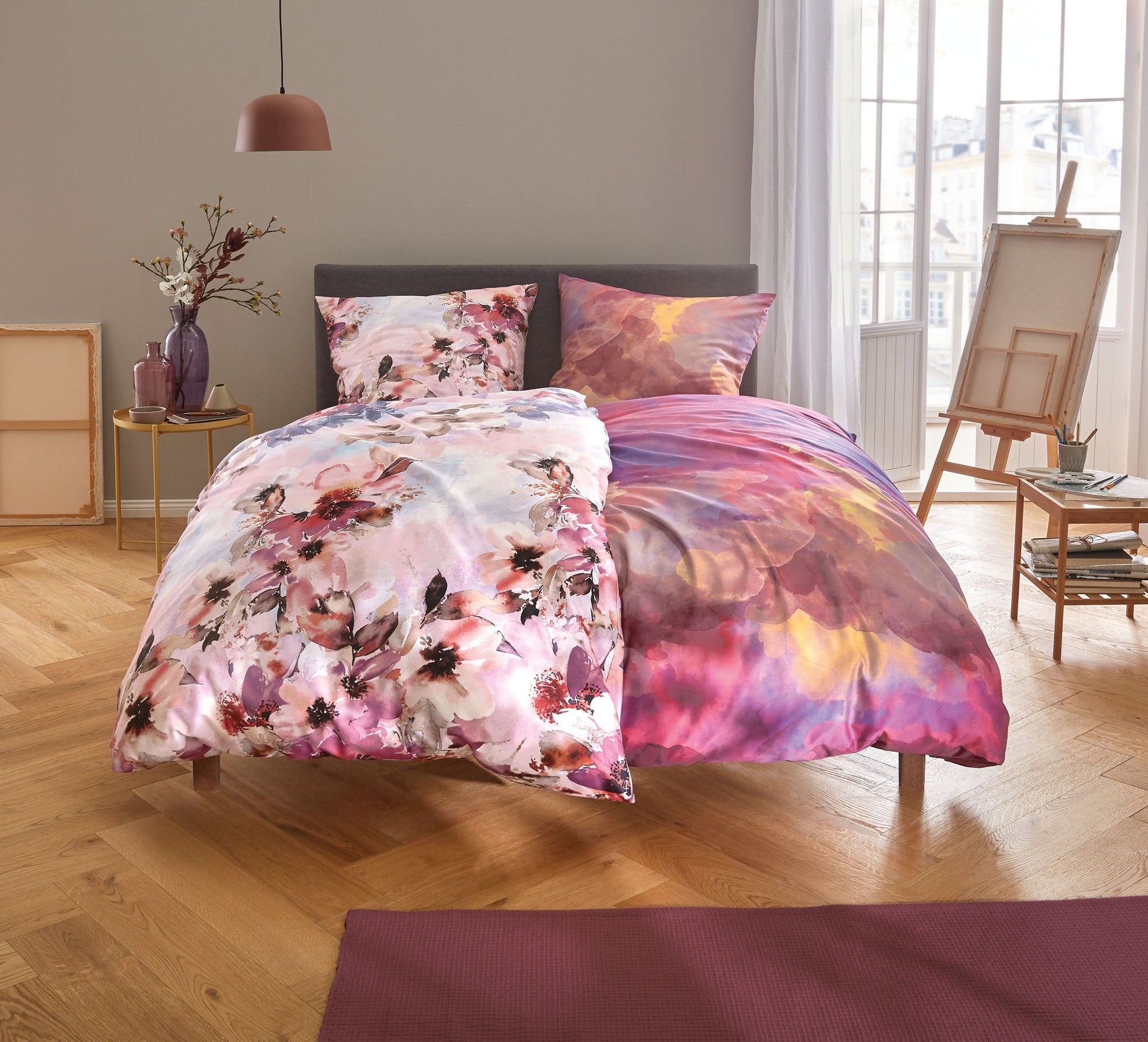 Doppelbett mit bunter Bettwäsche in Rosa- und Lilatönen im Schlafzimmer