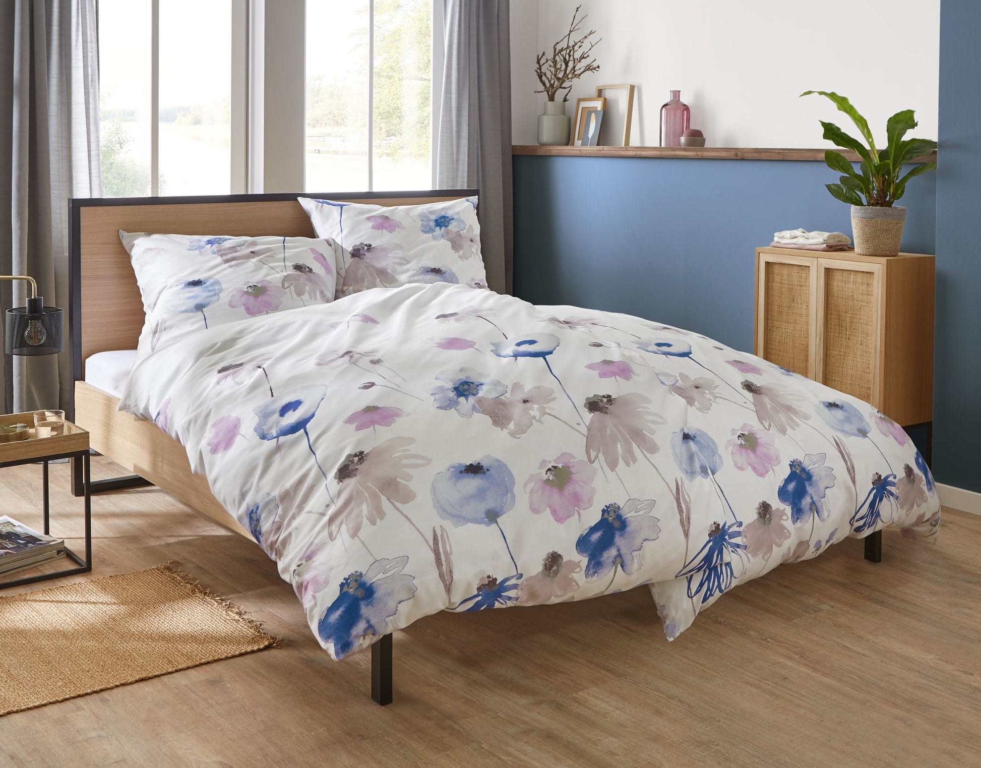 Bett mit weißer Bettwäsche mit Aquarell-Blumen in Blau und Rosa