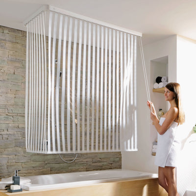 Frau zieht das Kleine Wolke Bubble Duschrollo über der Badewanne vor.