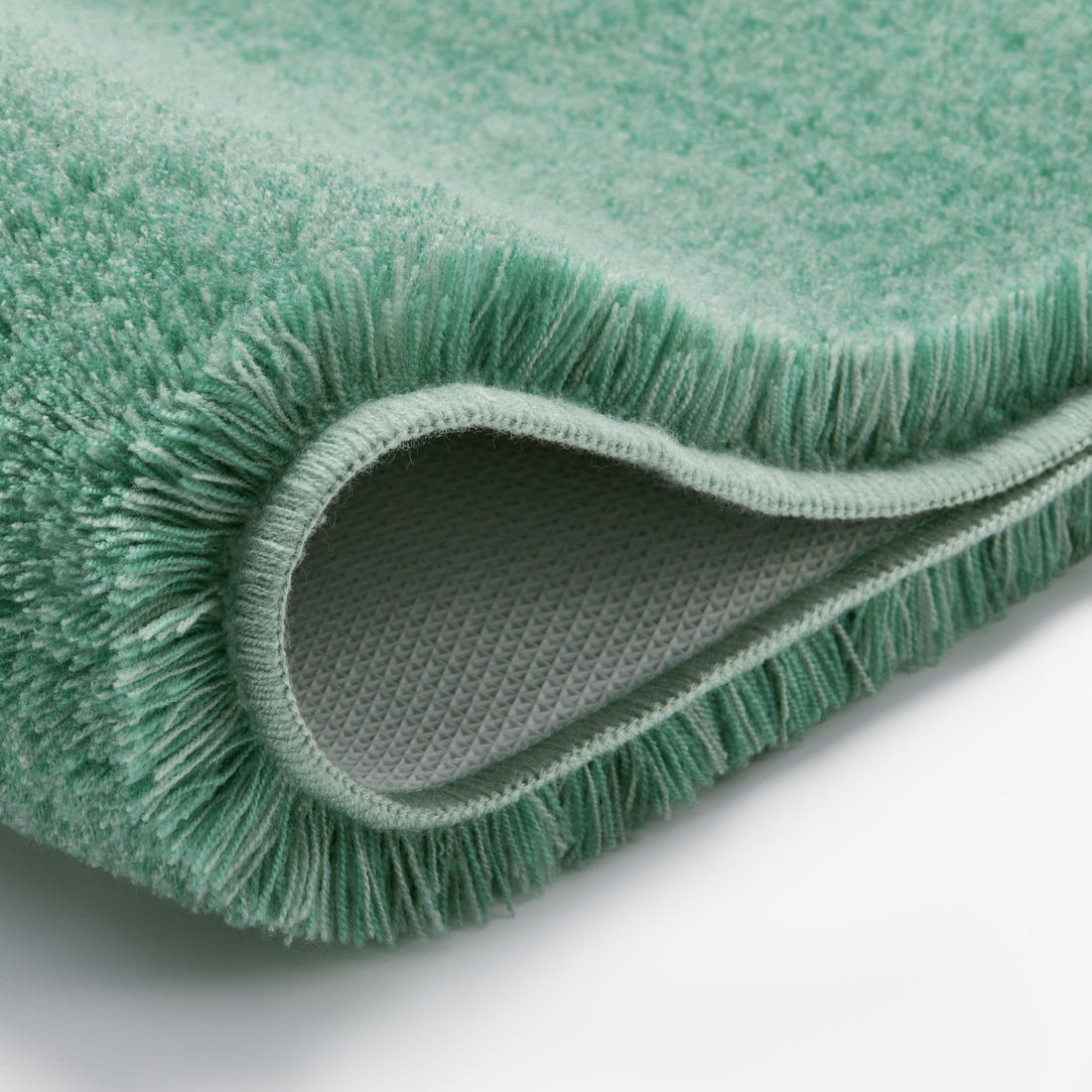 Grüner Badteppich mit weichem Flor und rutschfester Rückseite in Nahaufnahme.