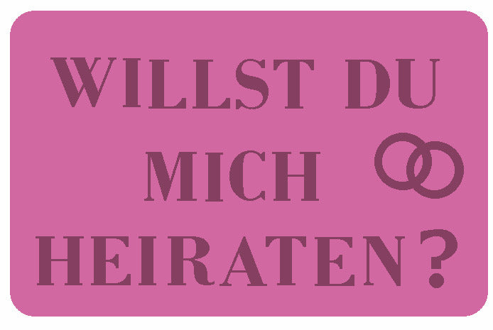 Rosa Badteppich mit Aufschrift Willst du mich heiraten und zwei ineinander verschlungenen Ringen.