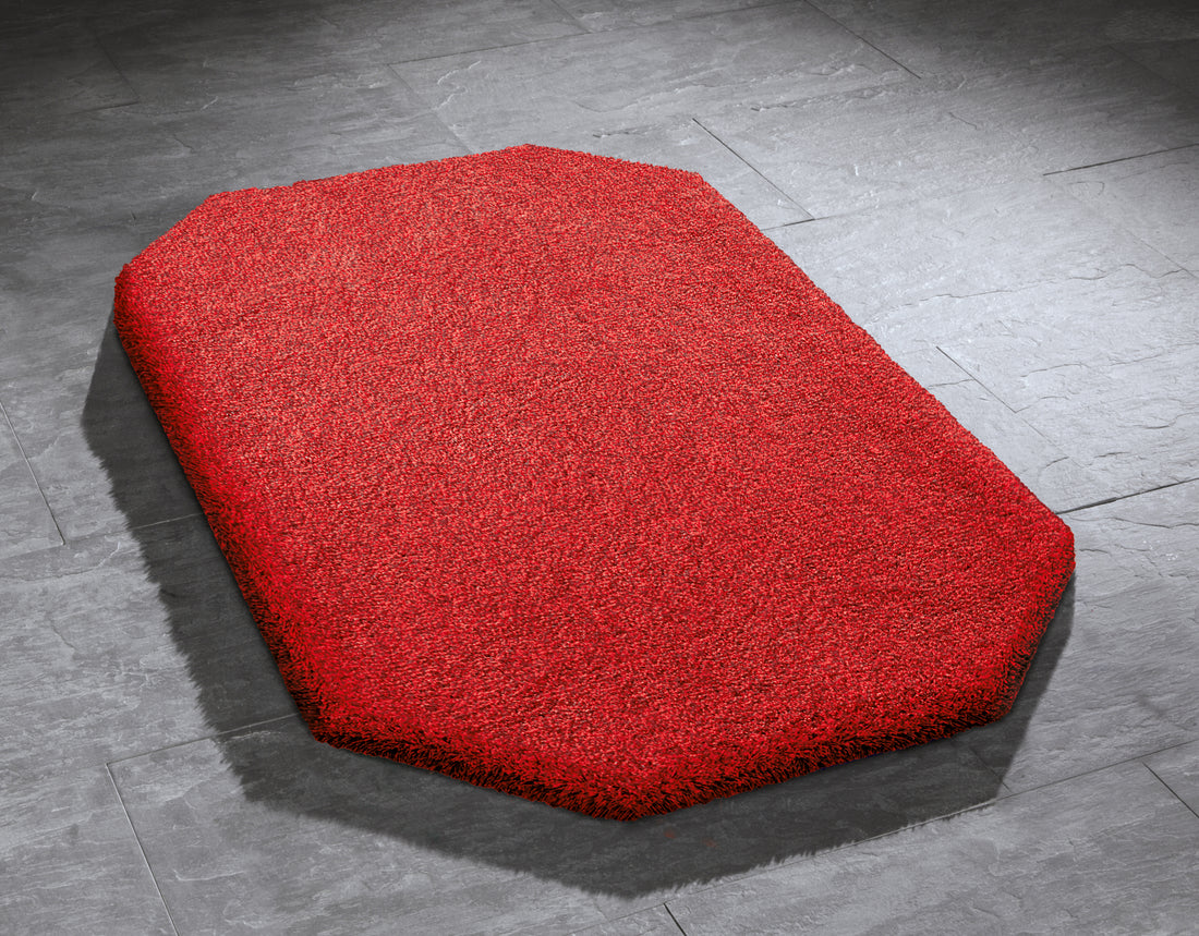 Roter Kleine Wolke Creativo Badteppich Relax liegt auf grauen Fliesen.
