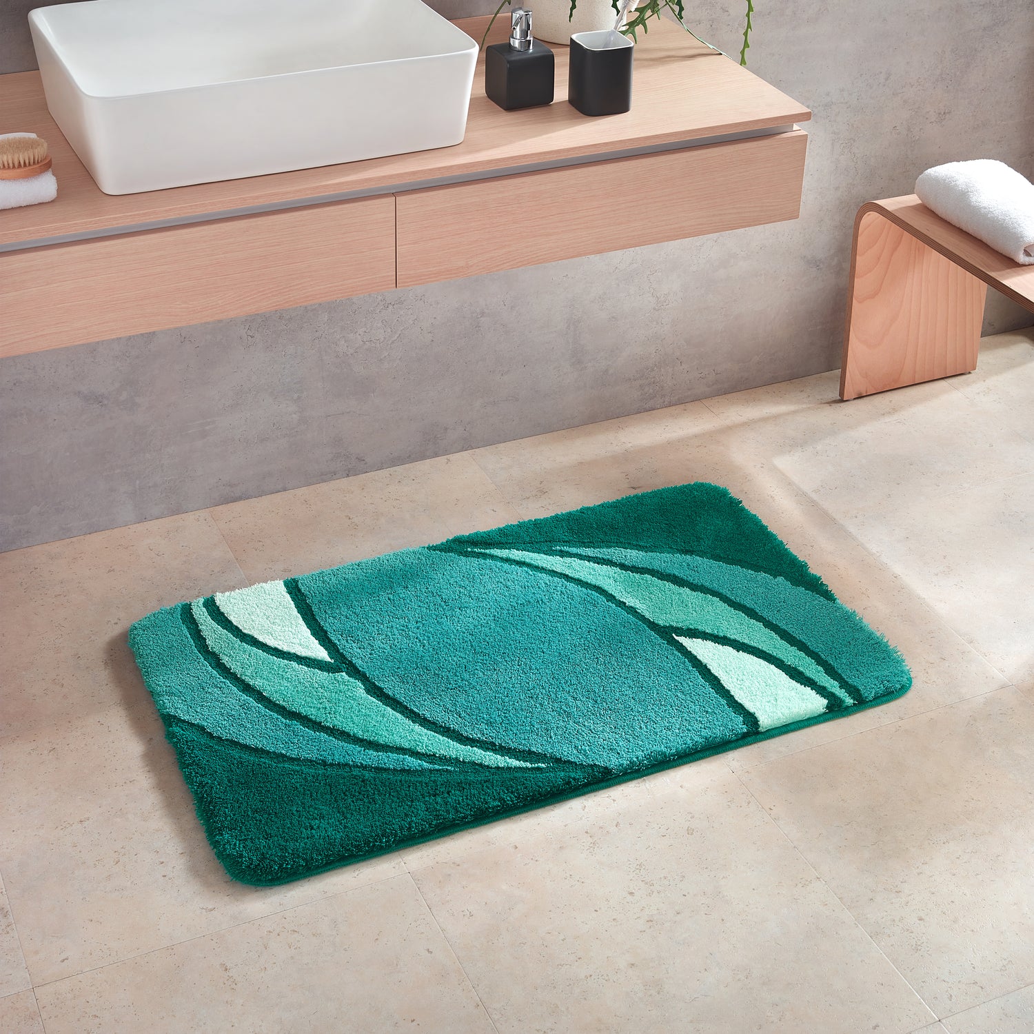 Badematte Kleine Wolke Creativo Collina in Grün liegt vor einem Waschbecken im modernen Bad.