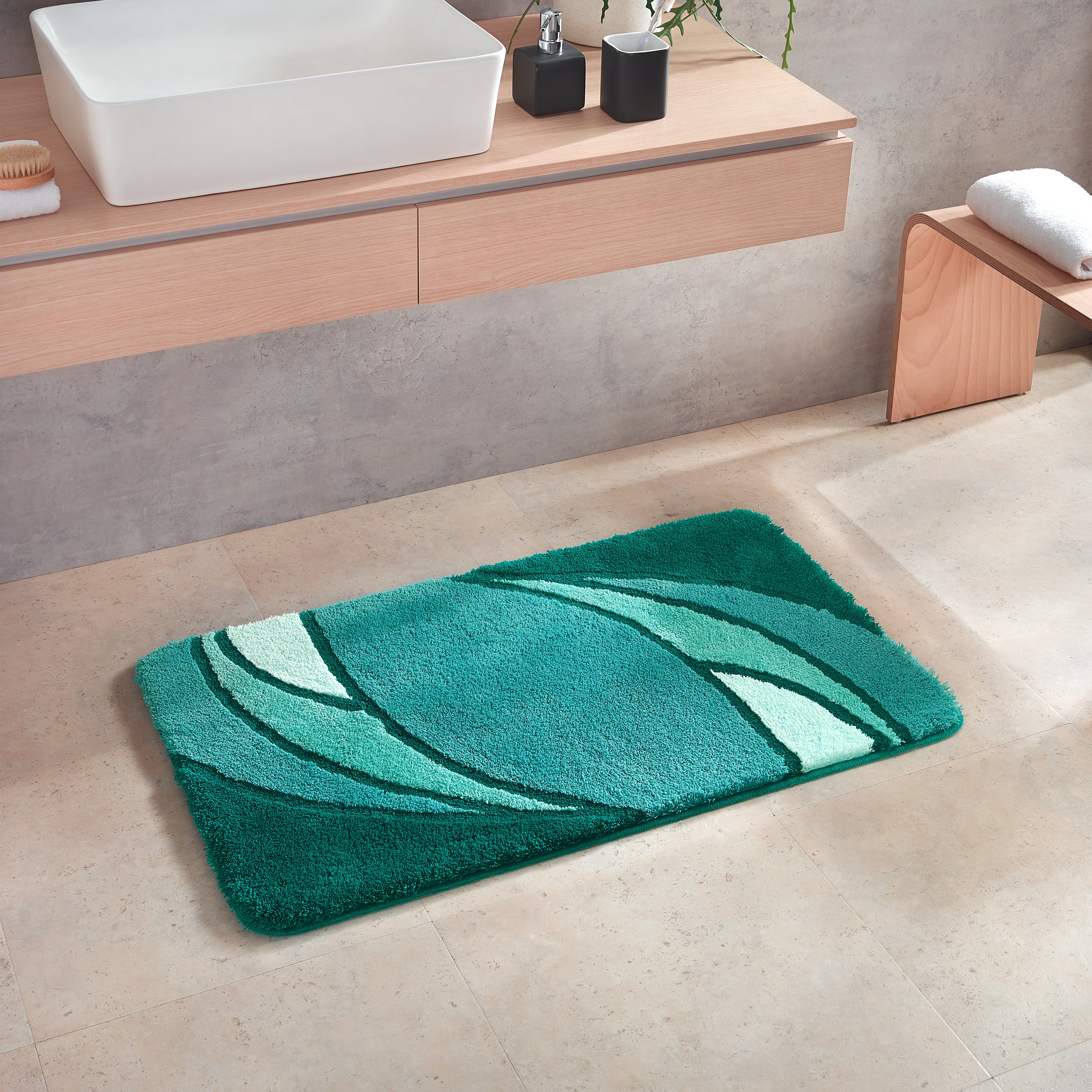 Badematte Kleine Wolke Creativo Collina in Grün liegt vor einem Waschbecken im modernen Bad.