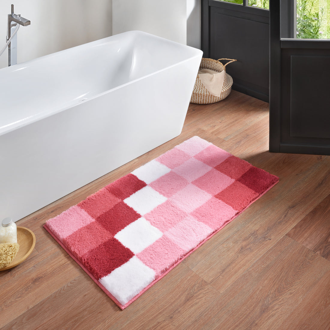 Rosa karierte Badematte Kleine Wolke Creativo liegt im Badezimmer vor einer weißen Badewanne.