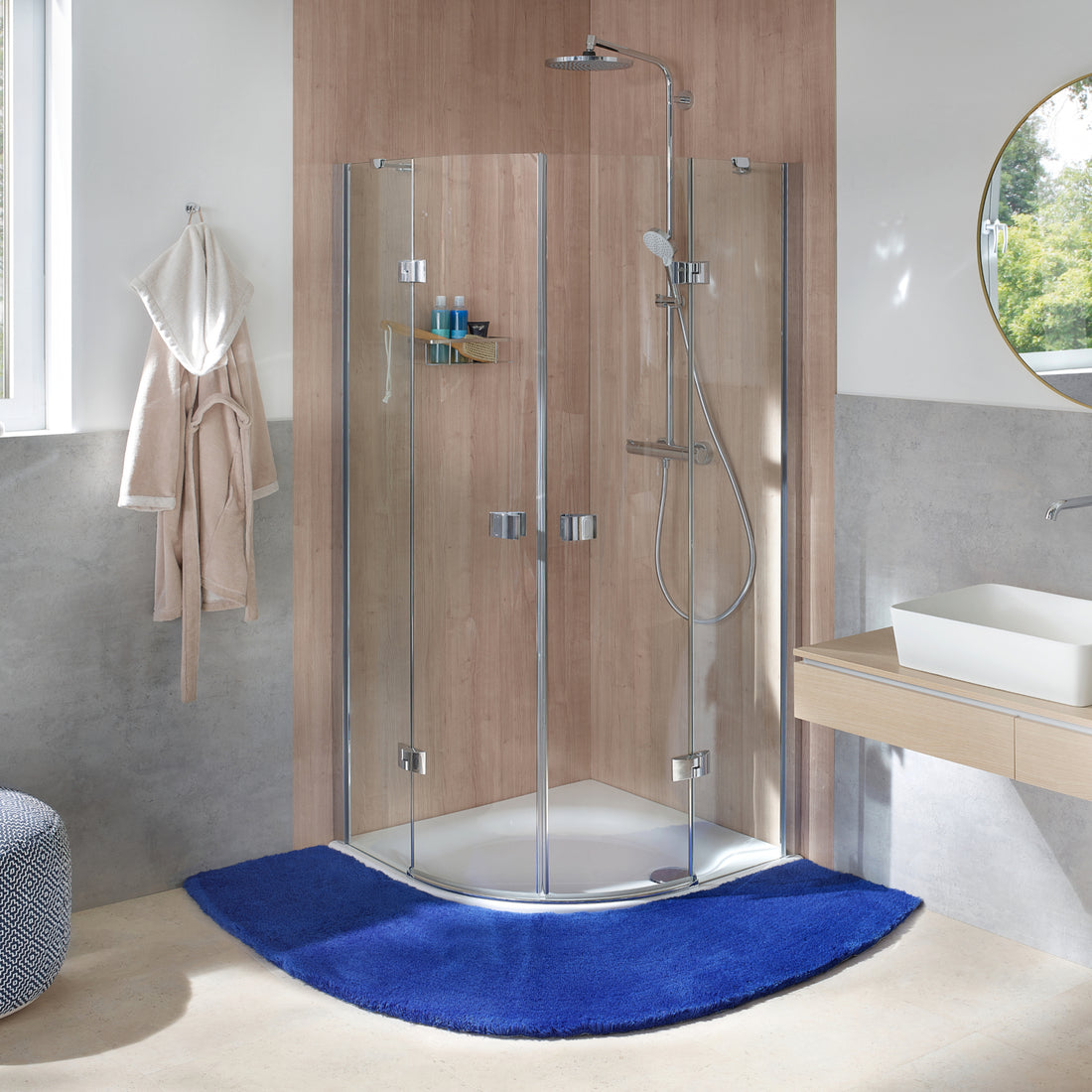 Blauer Kleine Wolke Creativo Badteppich liegt halbkreisförmig vor moderner Eckdusche im Badezimmer.