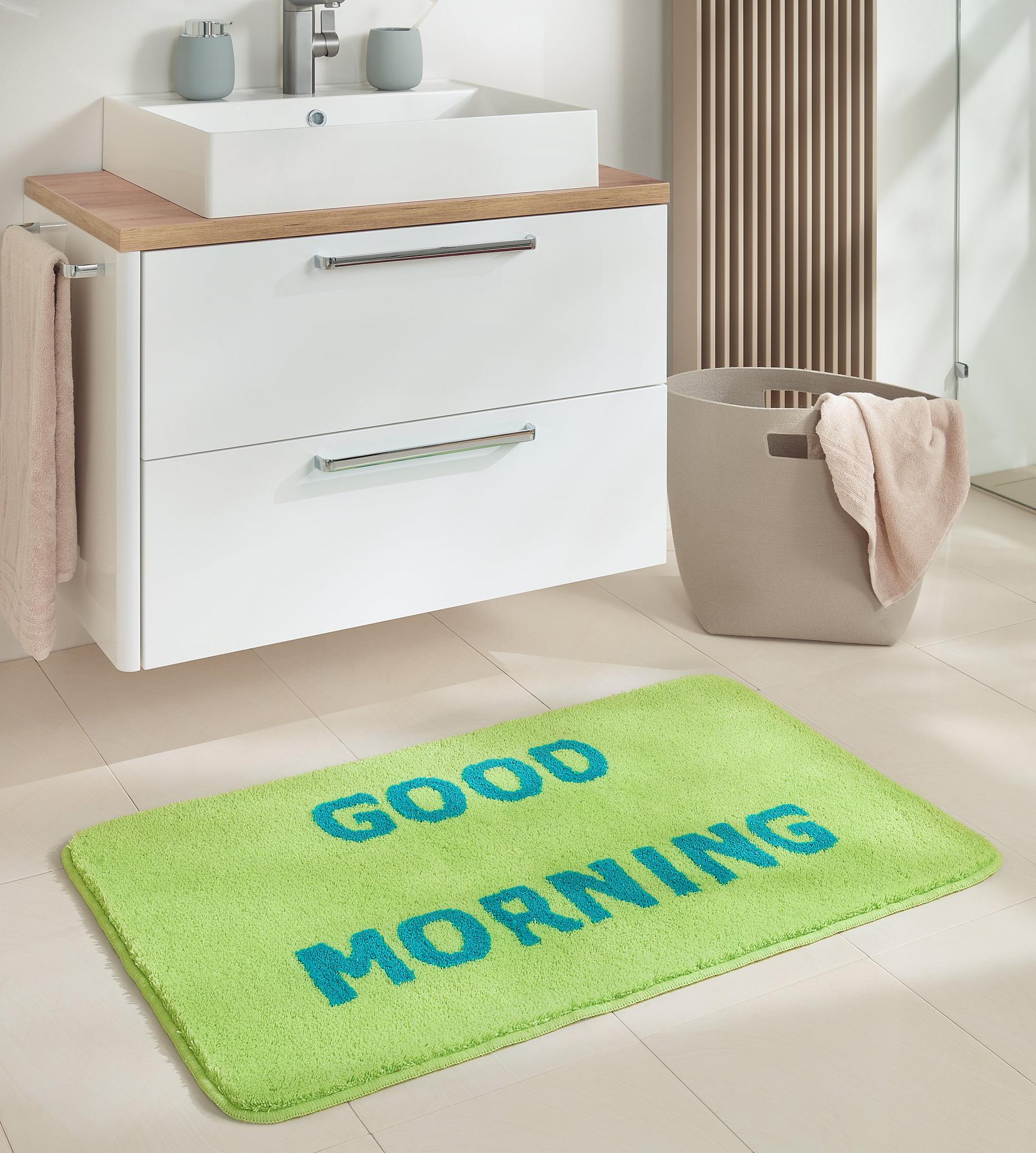 Grüne Badematte mit blauem Schriftzug GOOD MORNING vor Waschbecken