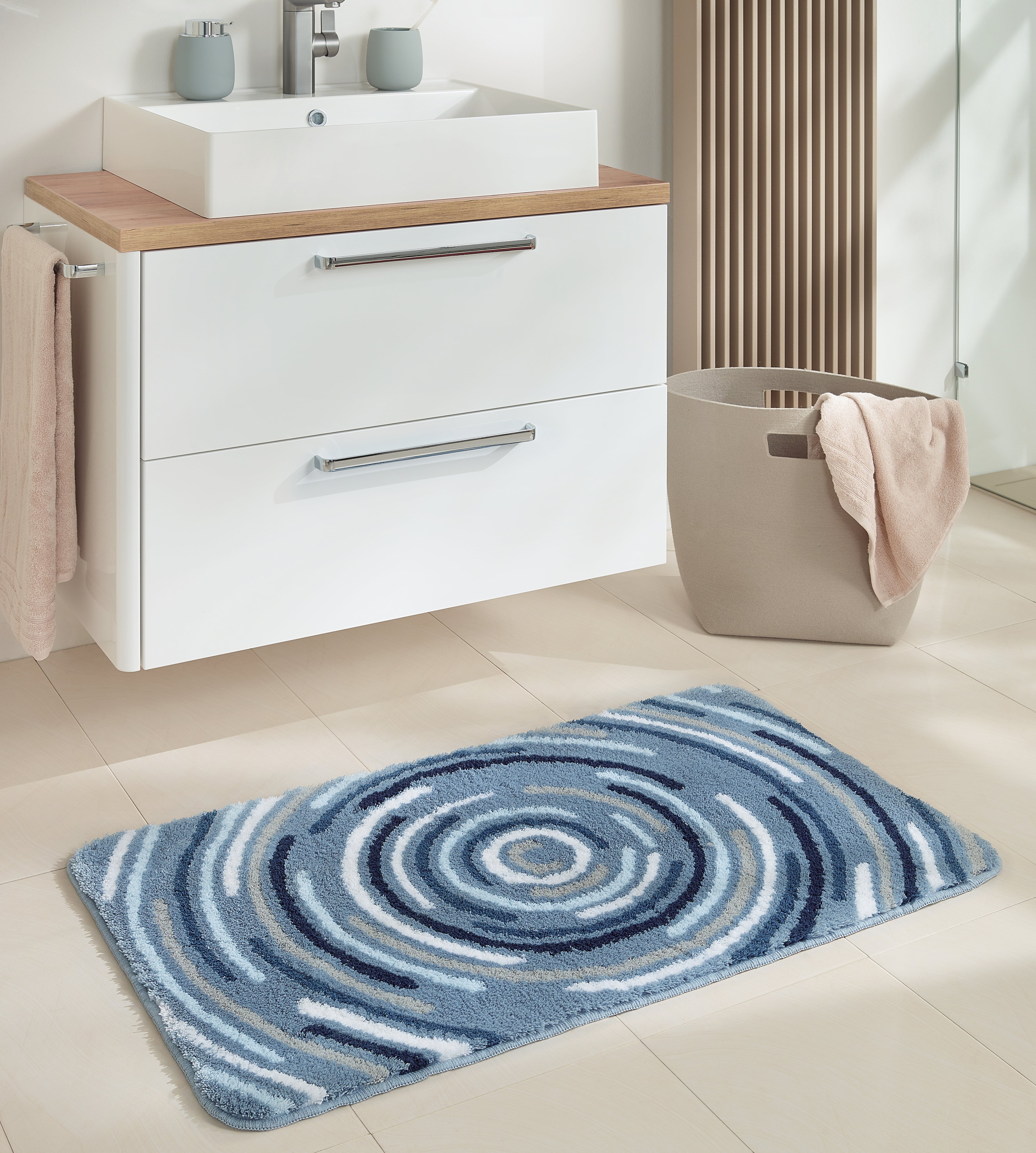 Badteppich Kleine Wolke Creativo Novero mit blauem Kreis-Muster vor Waschbeckenunterschrank.